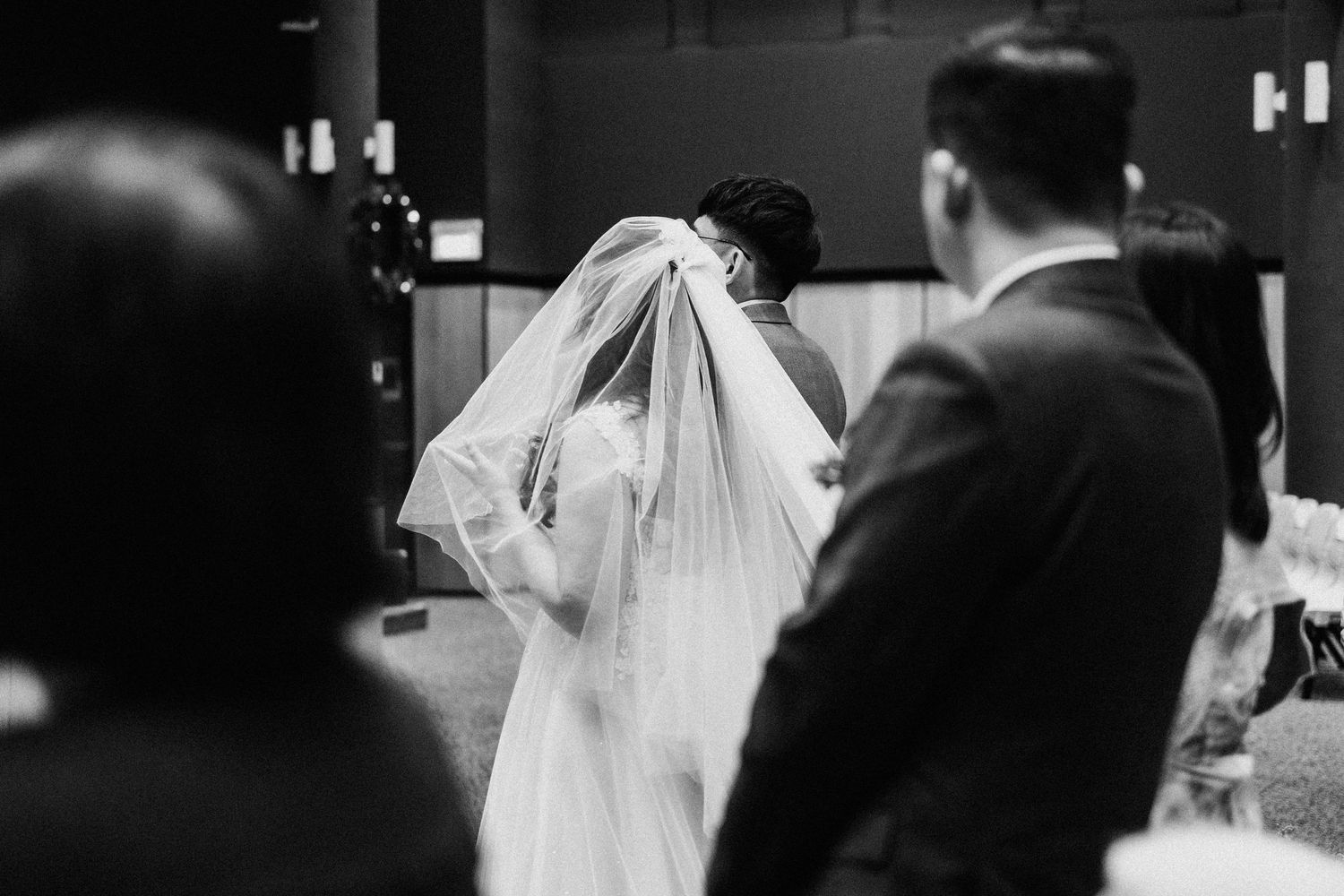A black and white photo capturing an intimate moment during a wedding ceremony.