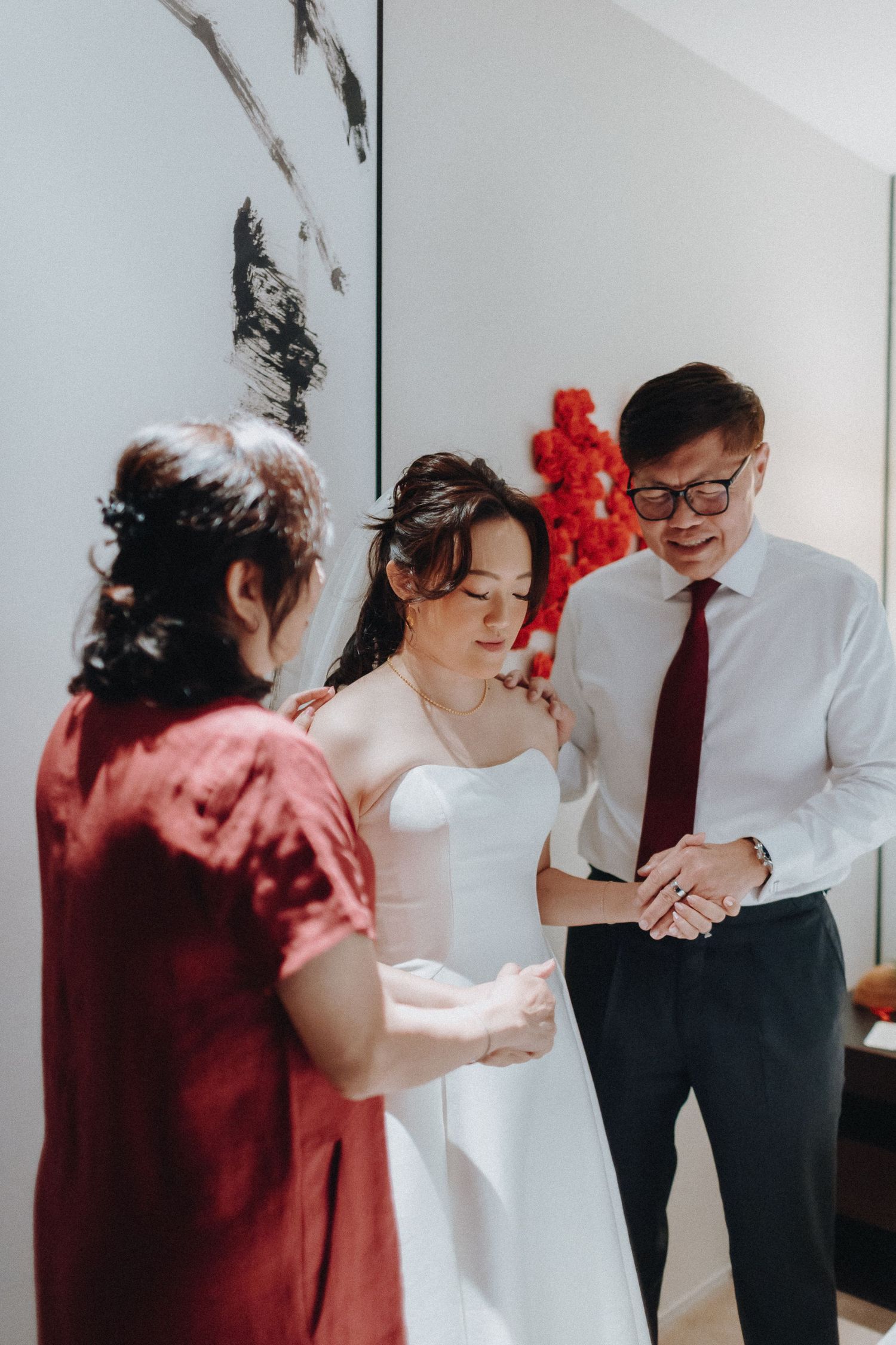 Couple sharing a tender moment in a white room with red accents during a wedding first look.