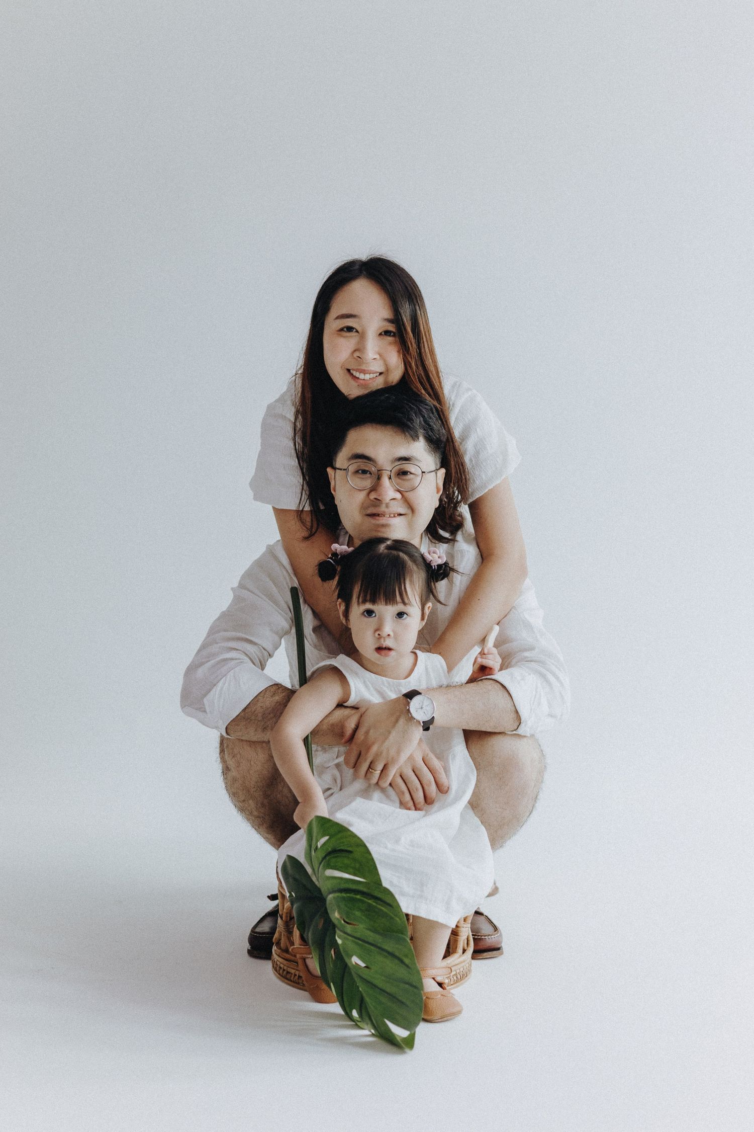 Intimate family photos show warm interactions on white background with tropical leaf accent.