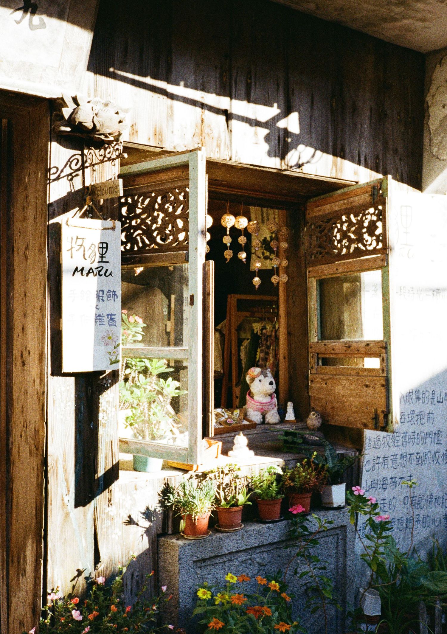 Traditional wooden building exterior with hanging plants and decorative elements in rustic setting.