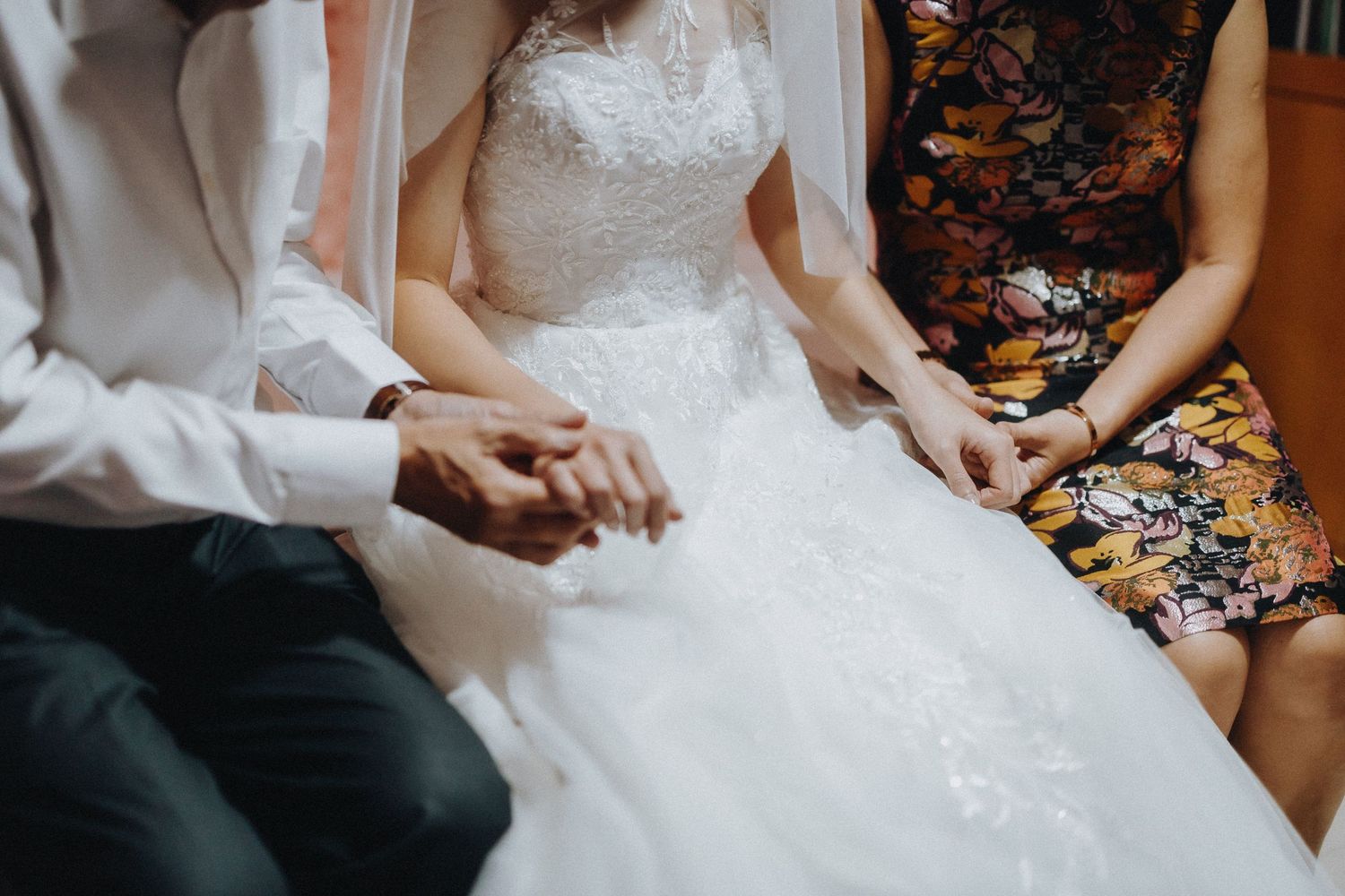 Close up detail shot of hands on white wedding dress fabric during pre-ceremony preparations.
