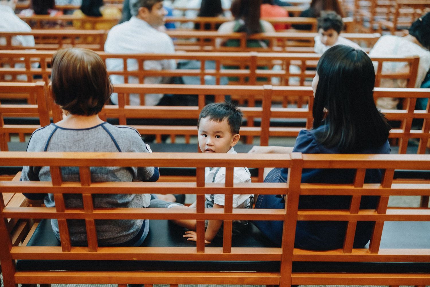 Guests seated on wooden benches at a formal ceremony venue.