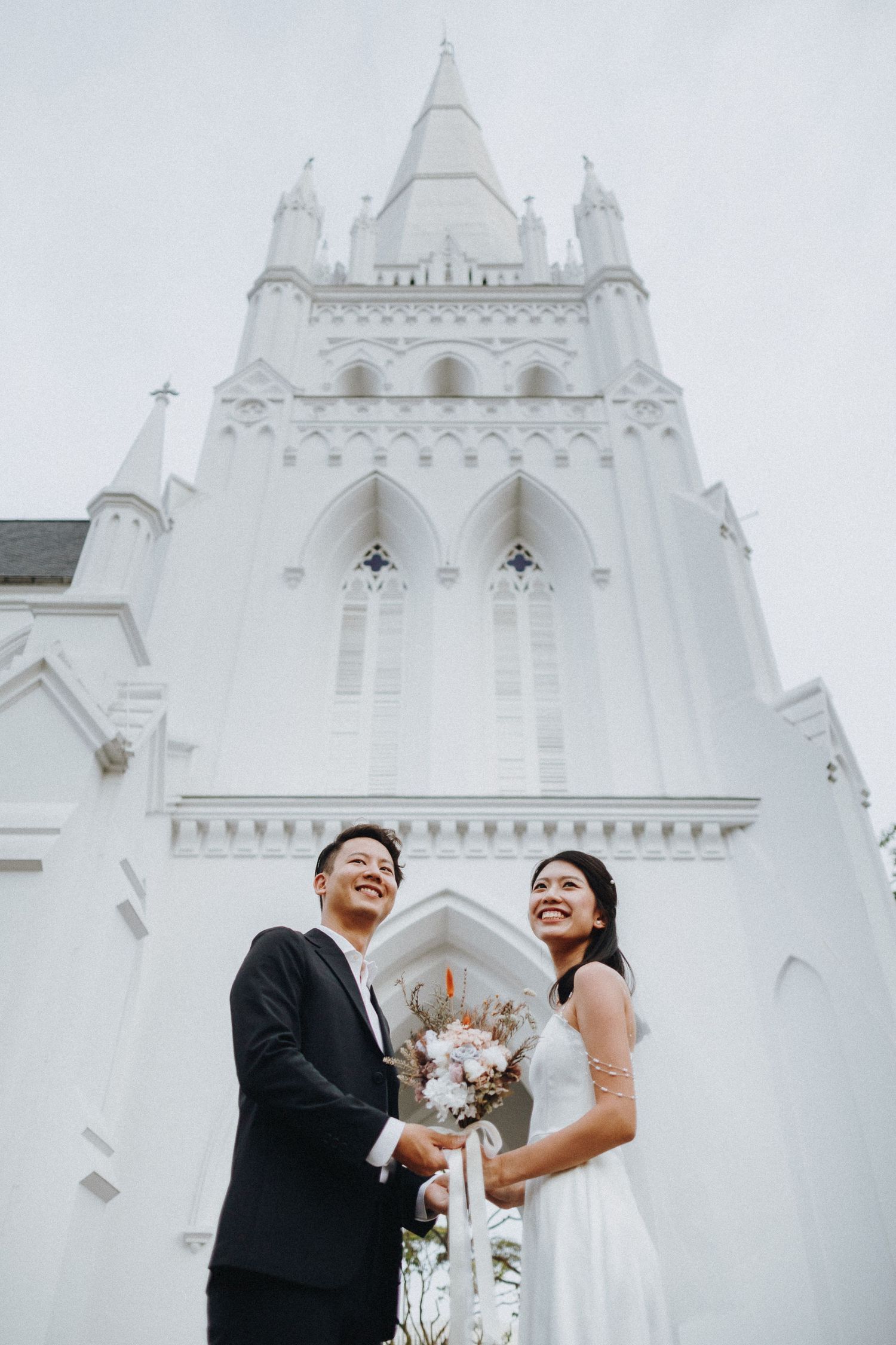 Wedding couple standing before majestic white gothic church spires.