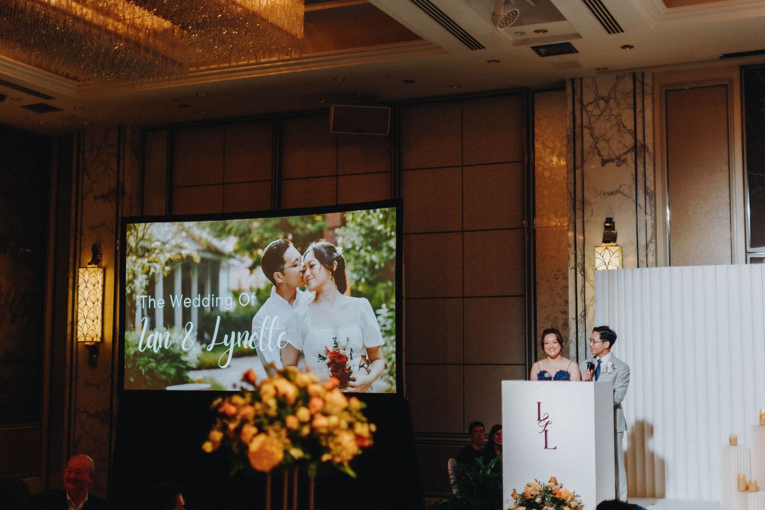 Wedding reception venue decorated with warm lighting and floral arrangements.