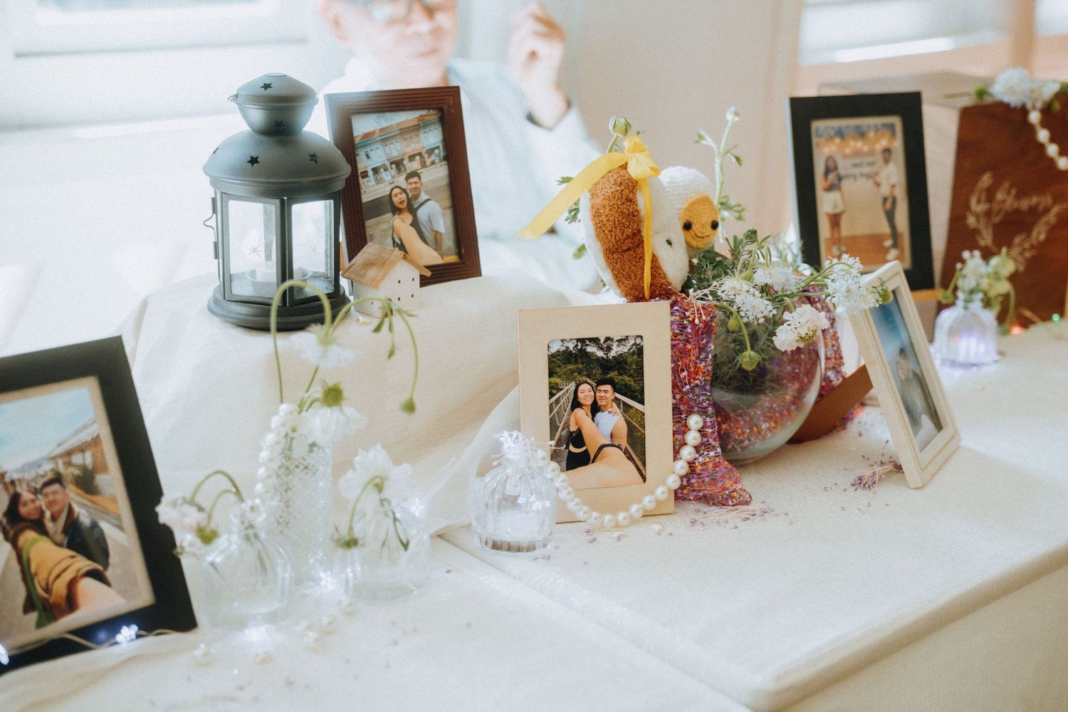 Wedding memory table with framed photos, lantern, flowers, and decorative keepsakes.
