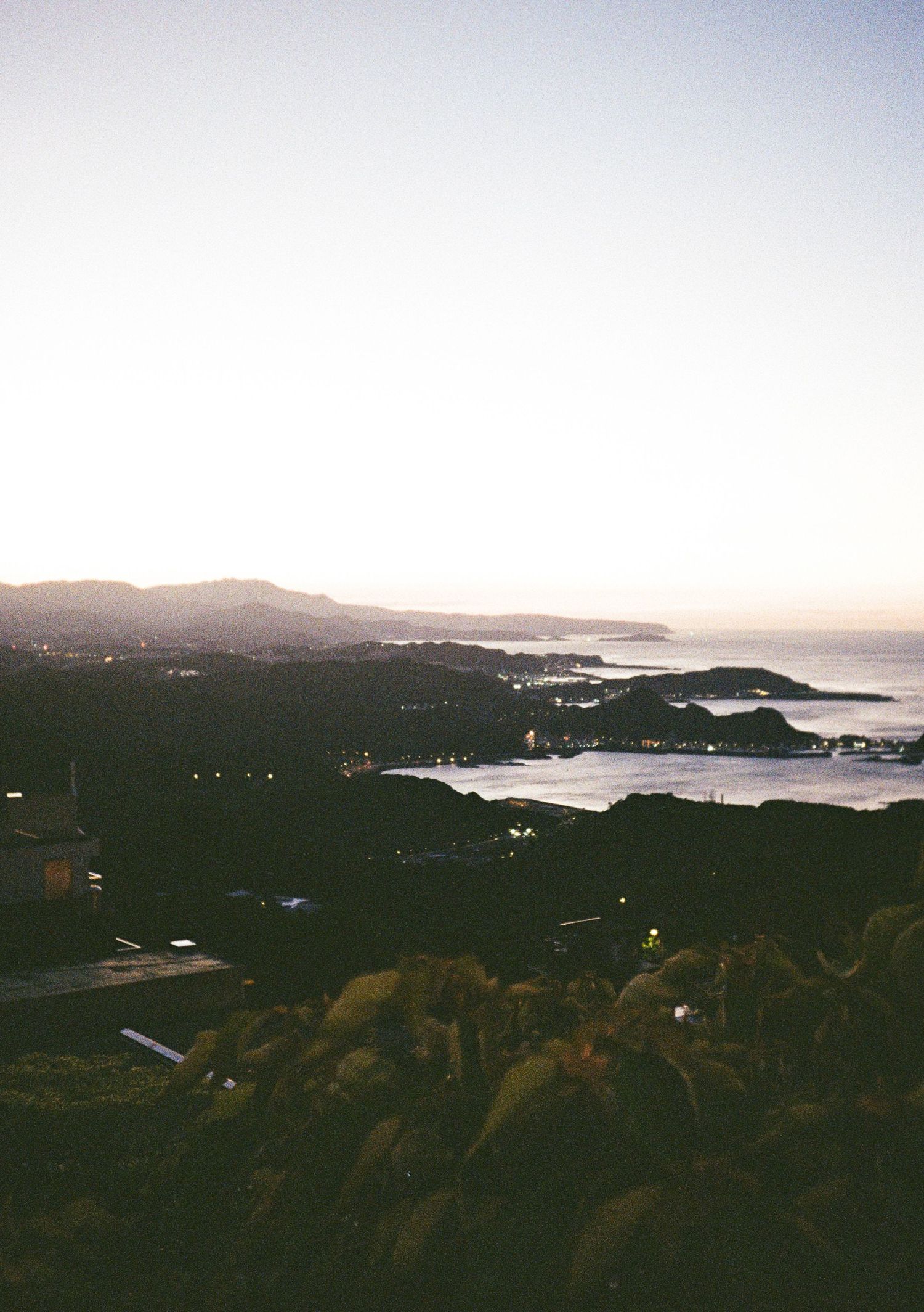 Mountain panorama overlooking coastal bay during twilight hours.