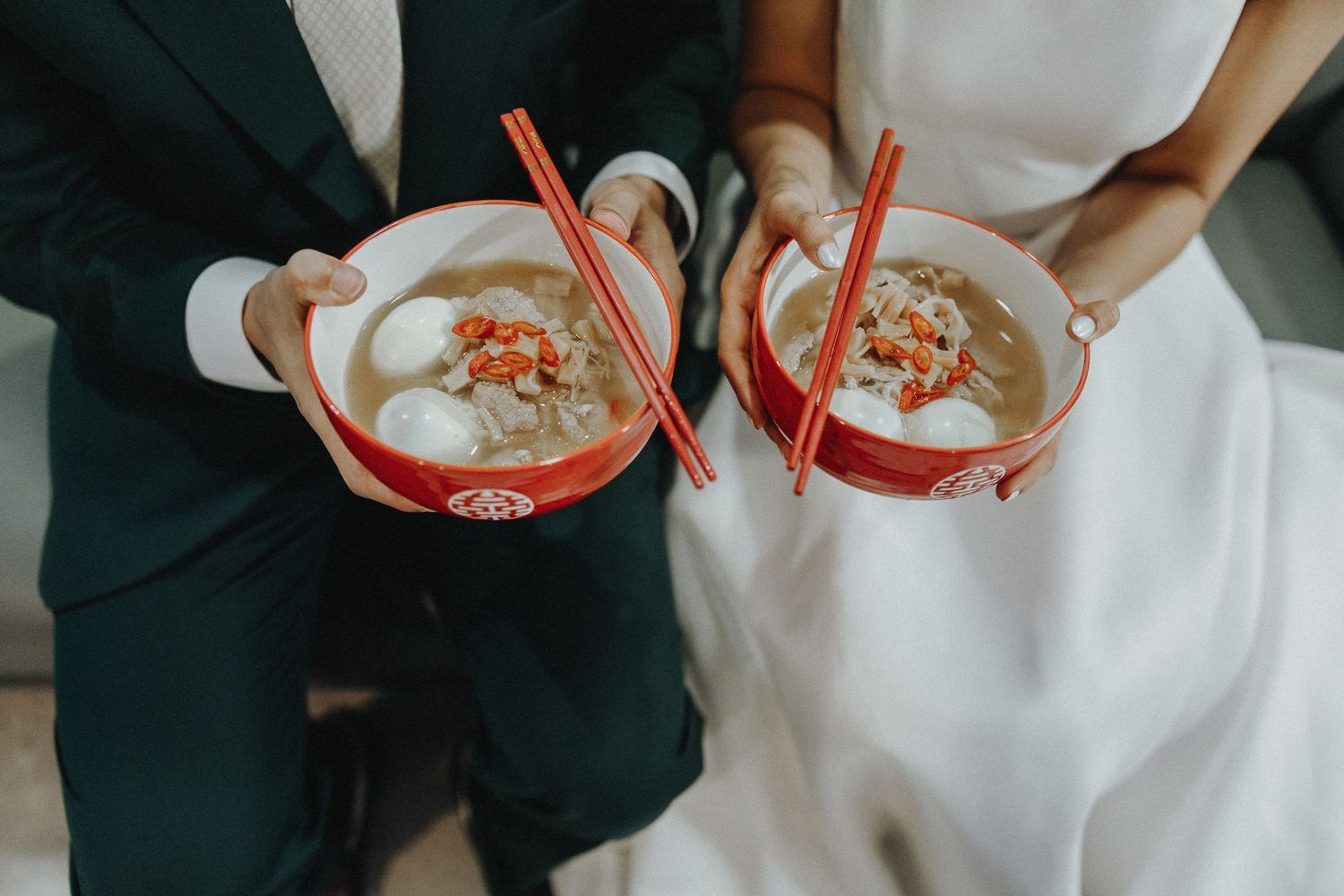 Wedding guests enjoying bowls of noodles at a reception celebration.