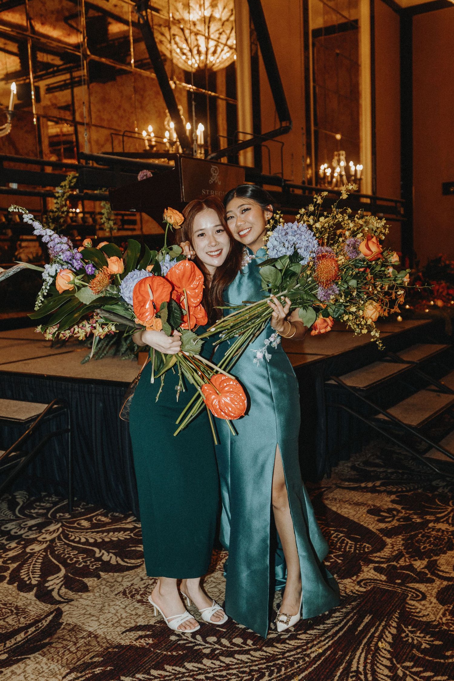 Elegant wedding reception setup with floral arrangements and chandeliers in warm lighting.