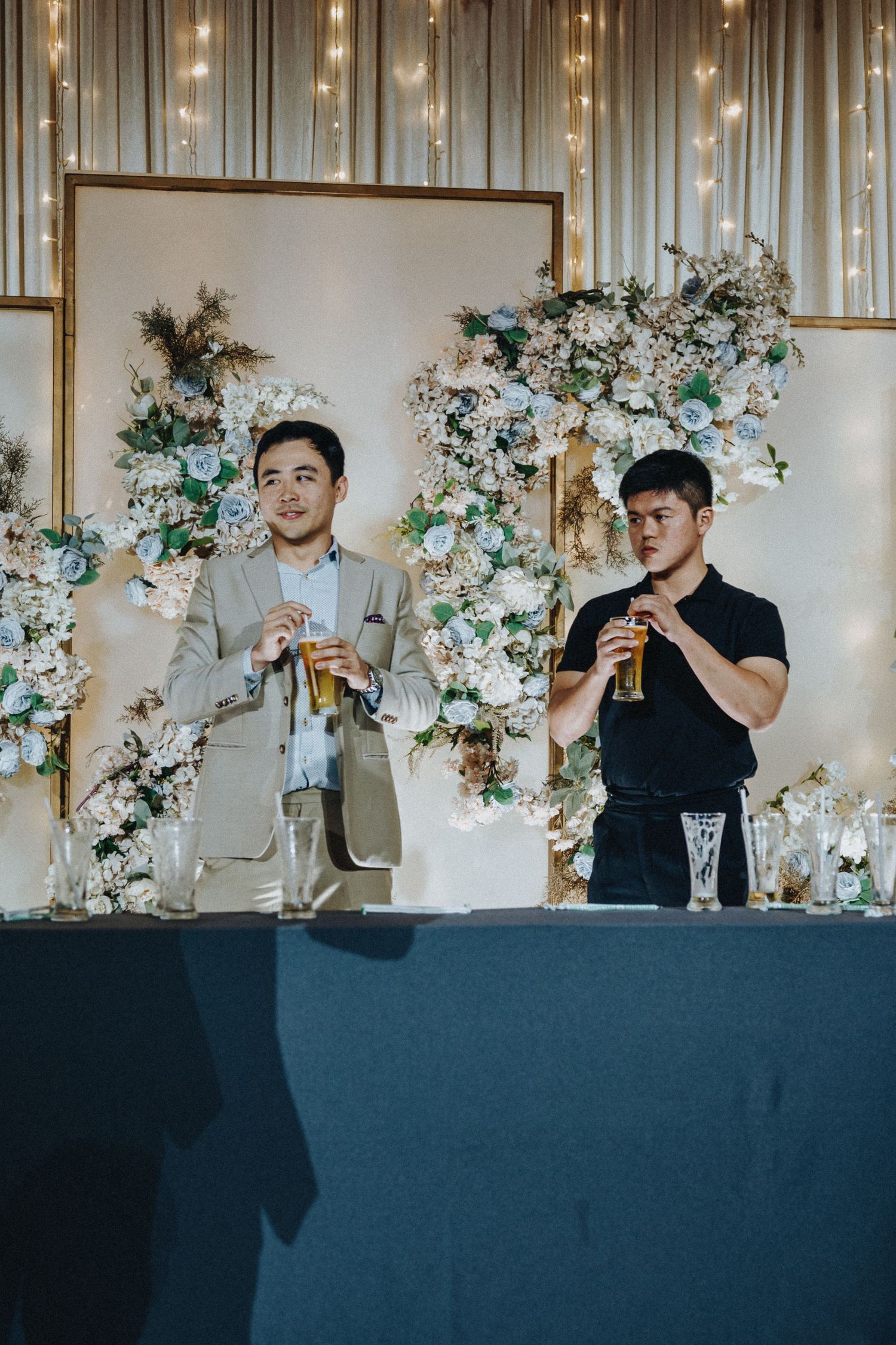 Wedding party members raise glasses for a toast at a decorated reception table.