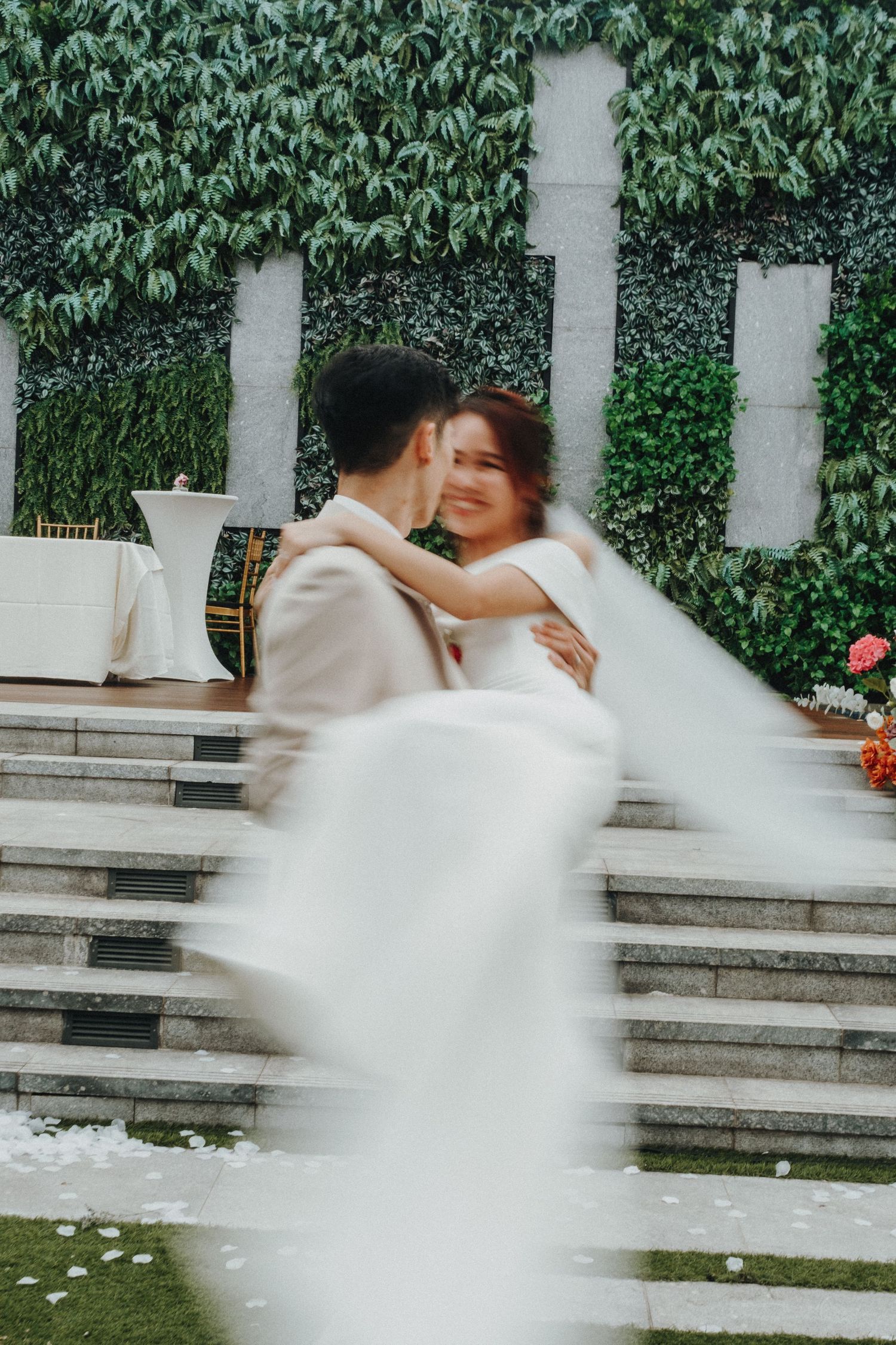 Romantic wedding couple spins and dances on stone steps with a lush green wall backdrop in sequential motion blur shots.