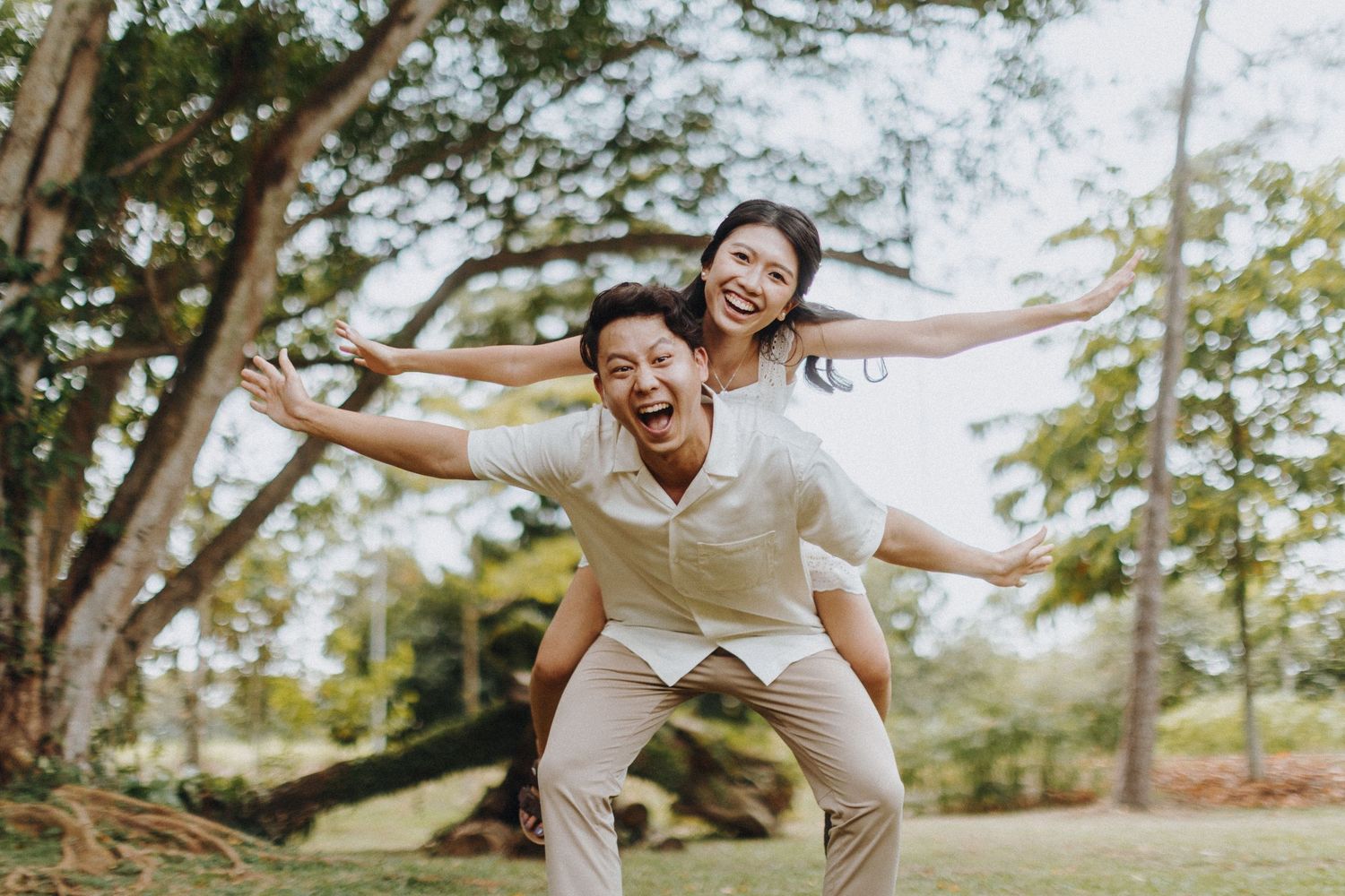 Playful moment captured outdoors with piggyback ride against natural backdrop.