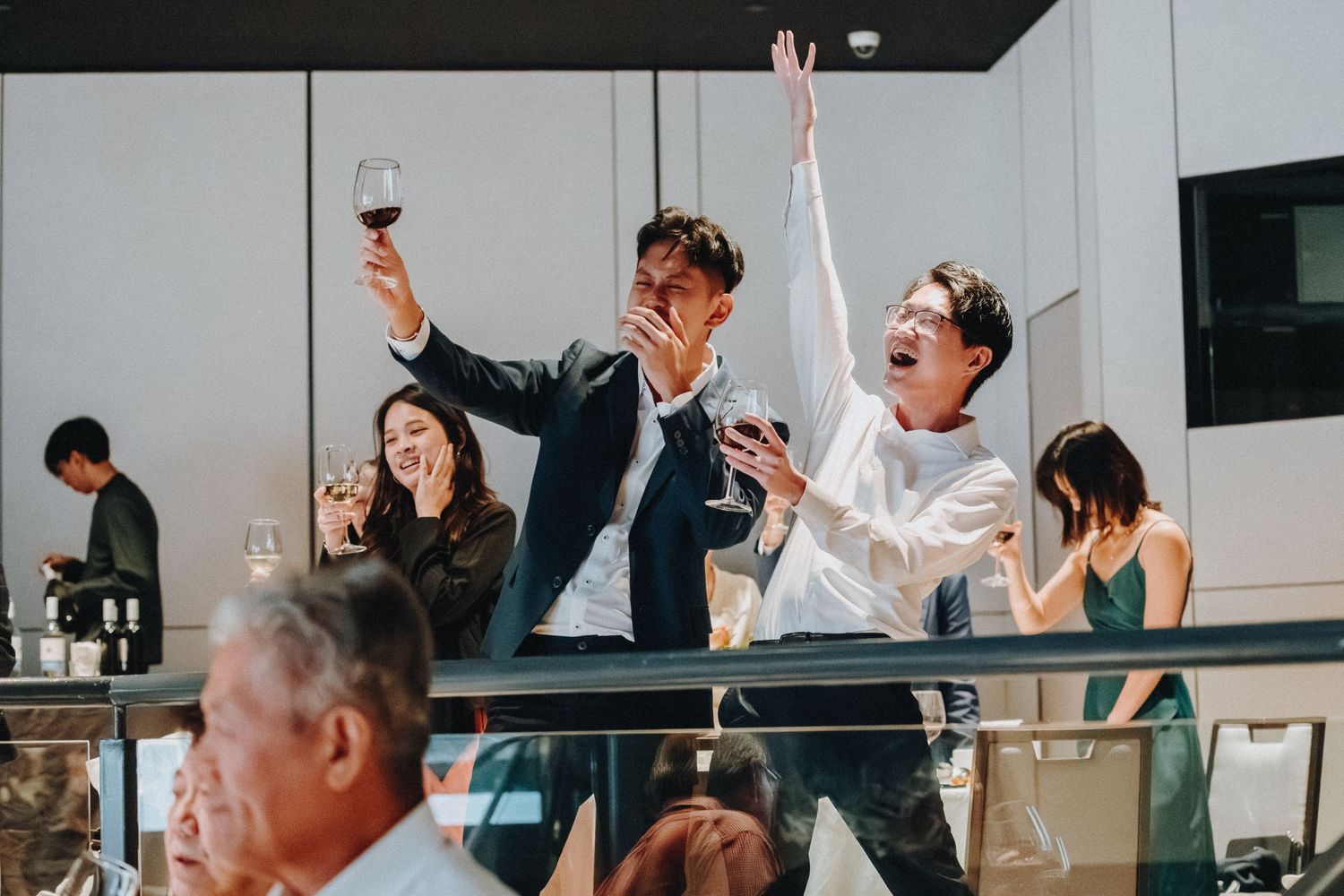 Wedding celebration with guests raising glasses in a toast during reception.