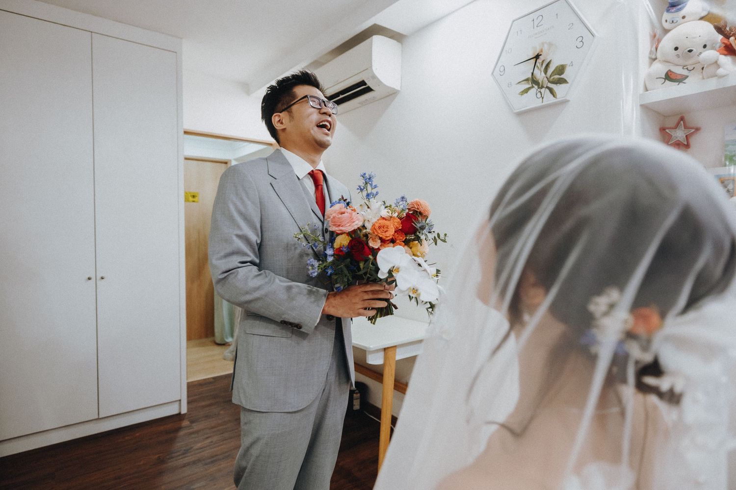 A tender moment between a couple on their wedding day, with the groom holding a vibrant bouquet of flowers.