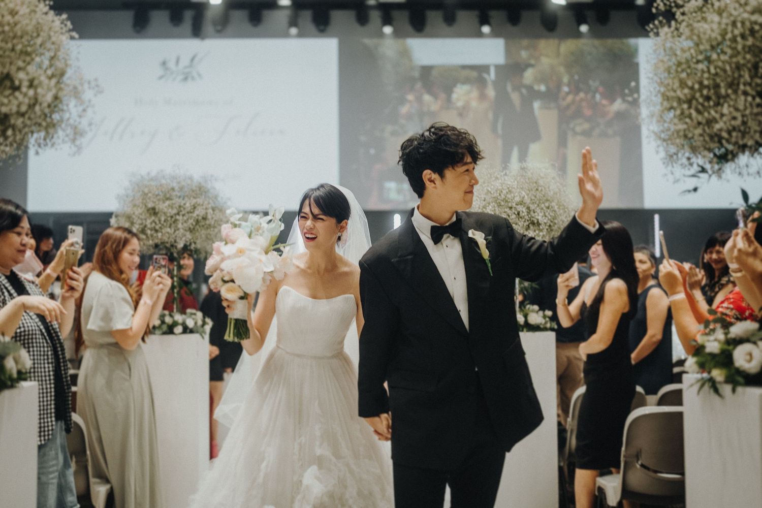 Wedding ceremony setup with white floral decorations and guests seated in rows.