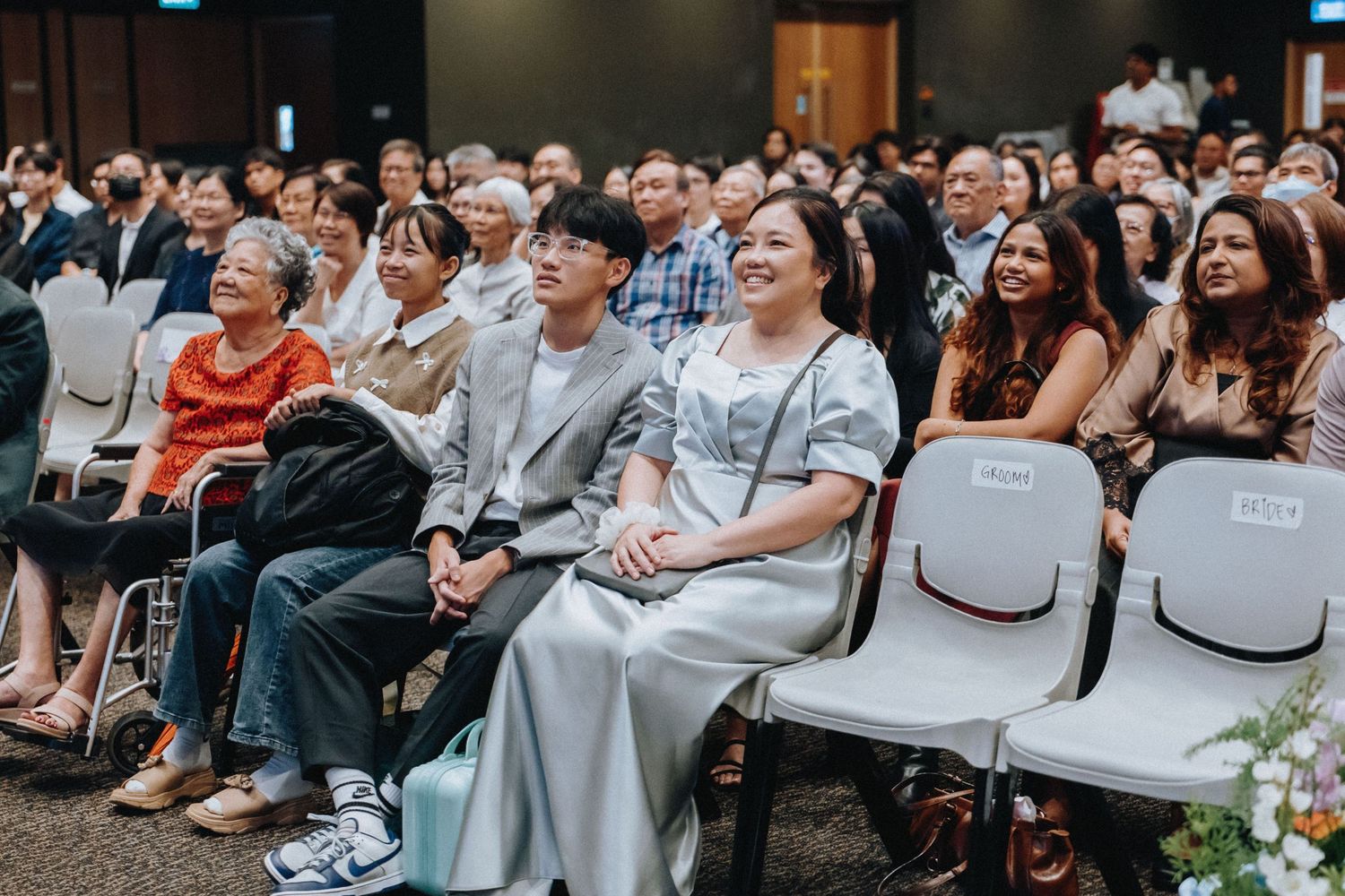 Audience members seated in chairs watching presentation with joyful expressions.