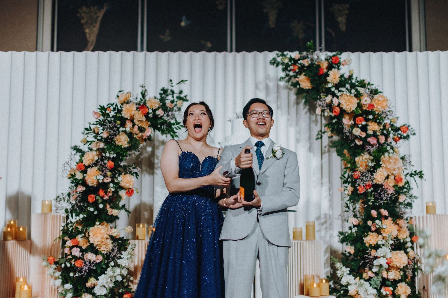 Wedding reception space decorated with peach floral arrangements and white panels.