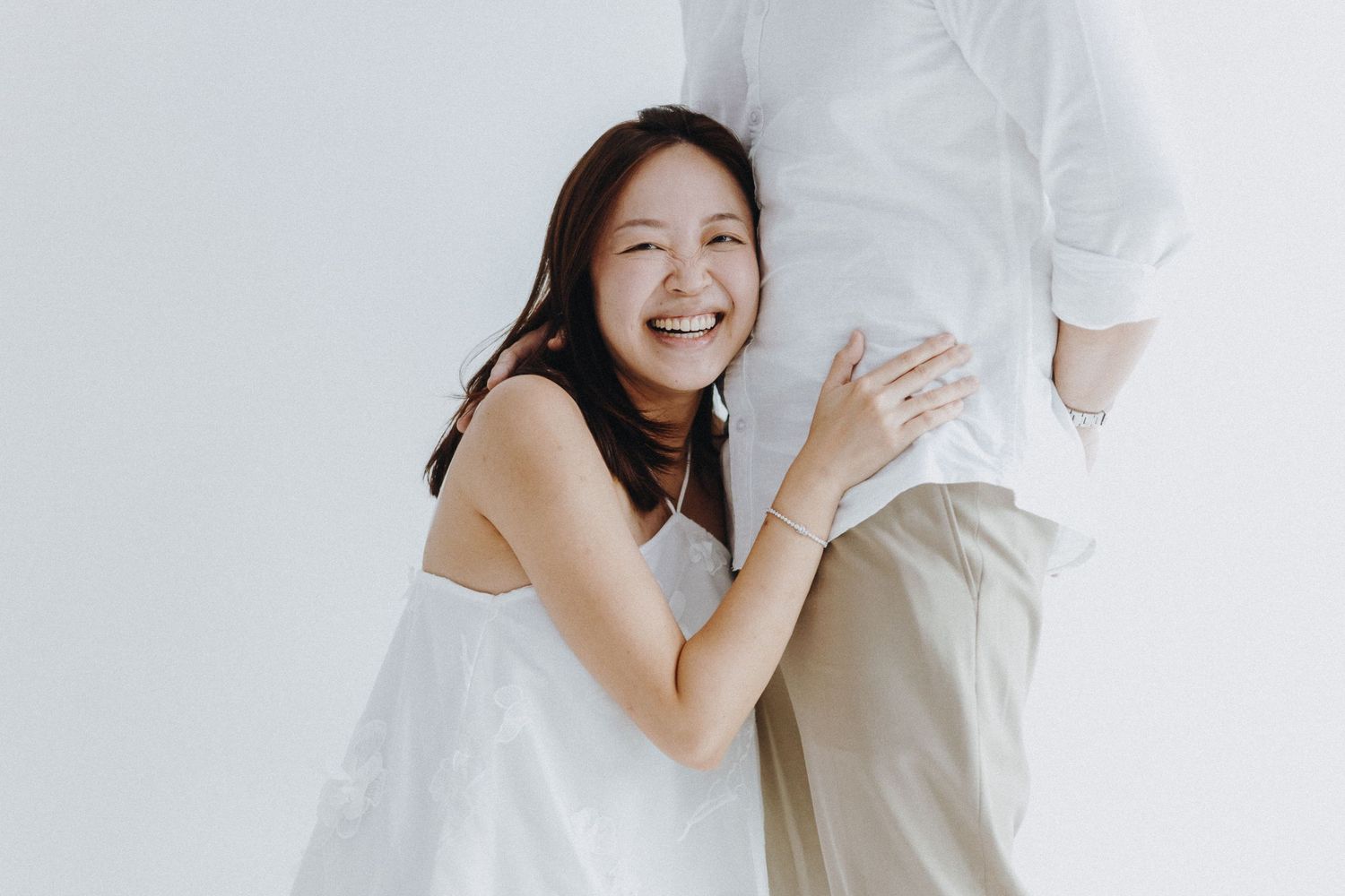 Romantic couple sharing intimate moments in a bright white studio setting.