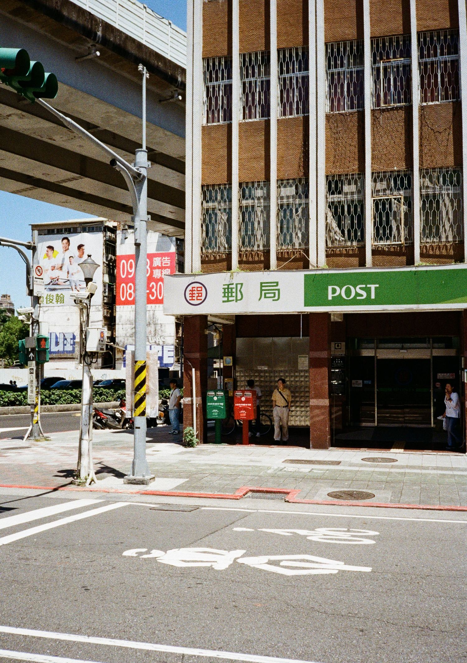 Japanese post office exterior with signs and parking area on a quiet street.