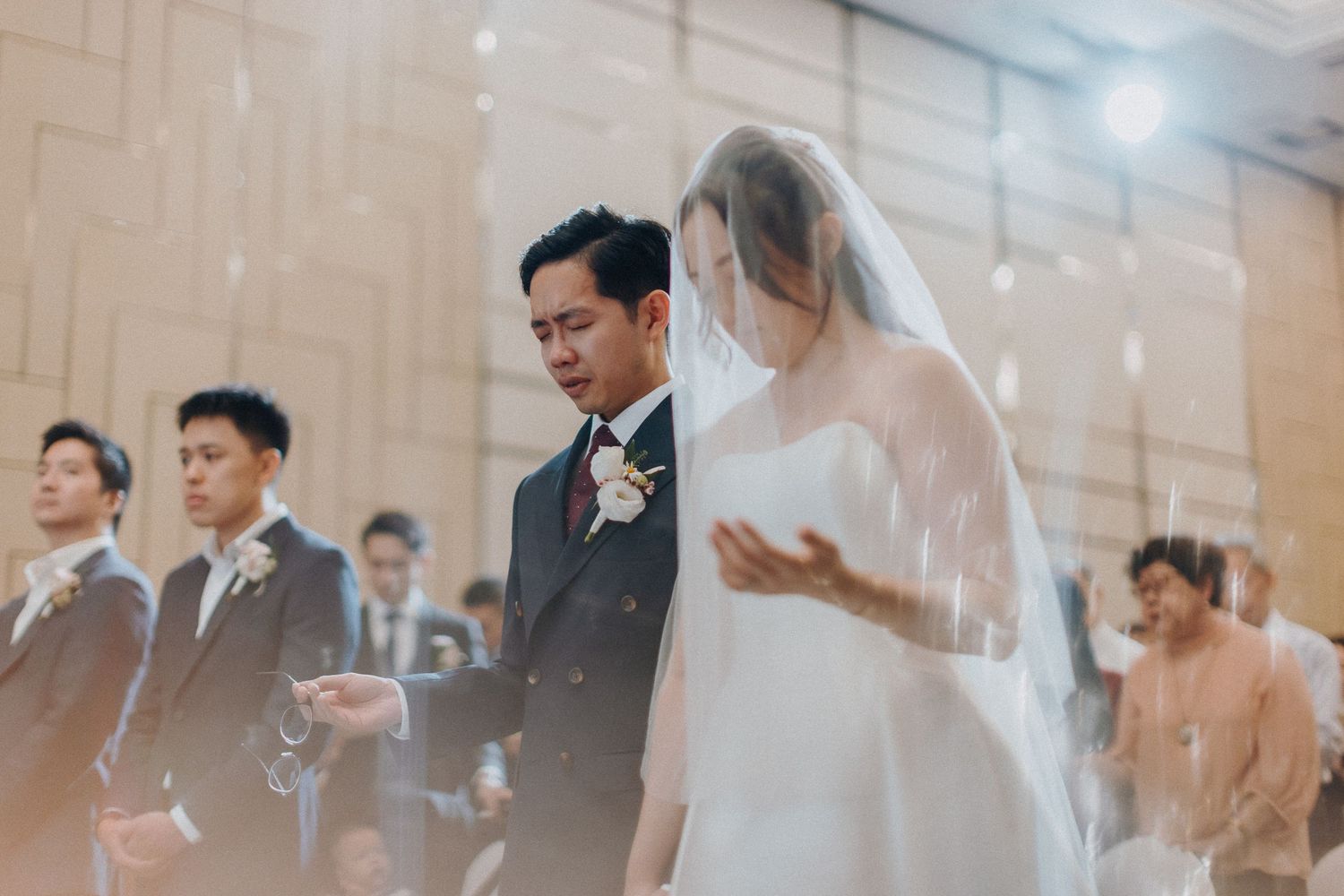 Wedding ceremony in progress with guests seated in an elegantly decorated venue.