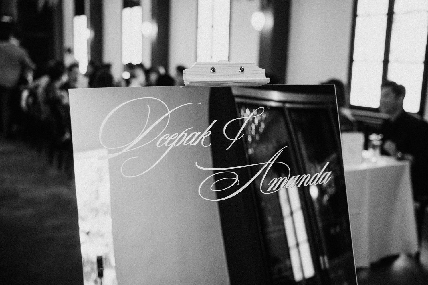 Black and white photo of elegant wedding sign reading Deepak and Amanda at reception.