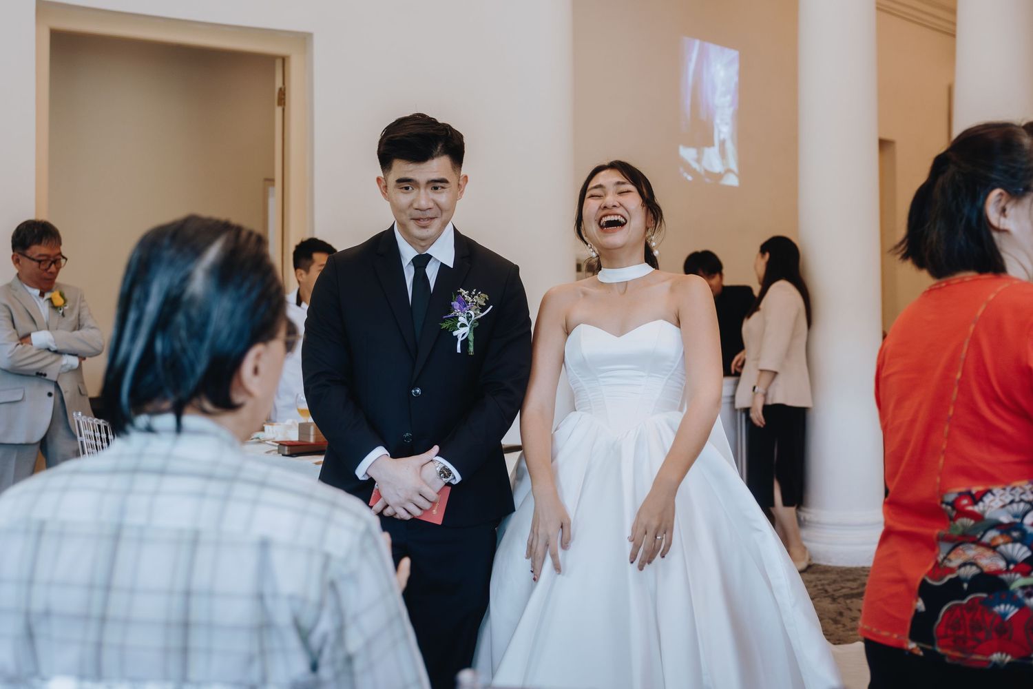 Bride laughs joyfully with groom in classic white ballgown during wedding reception.
