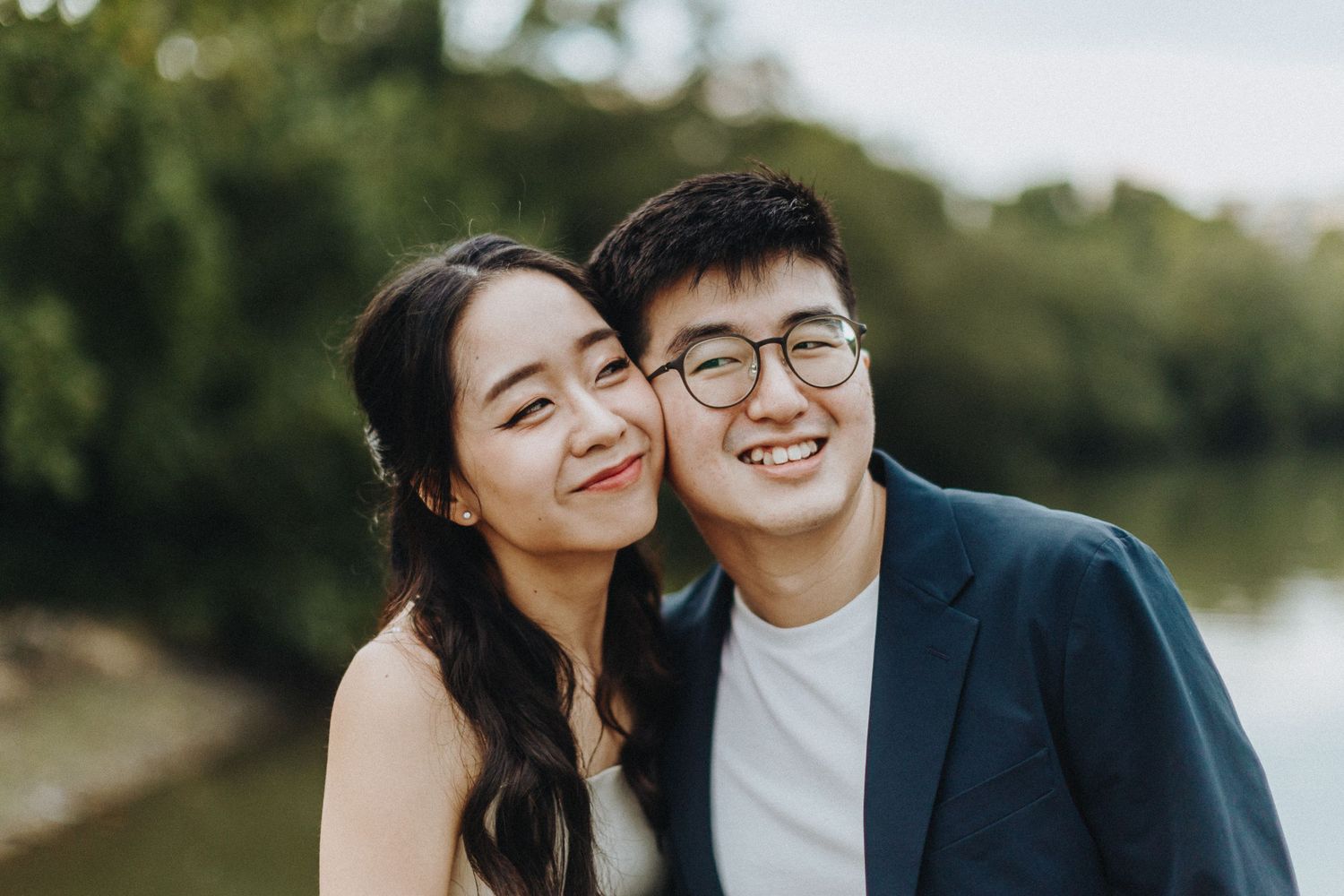 A joyful couple embraces outdoors at sunset while sharing laughter and affectionate moments in a photoshoot.