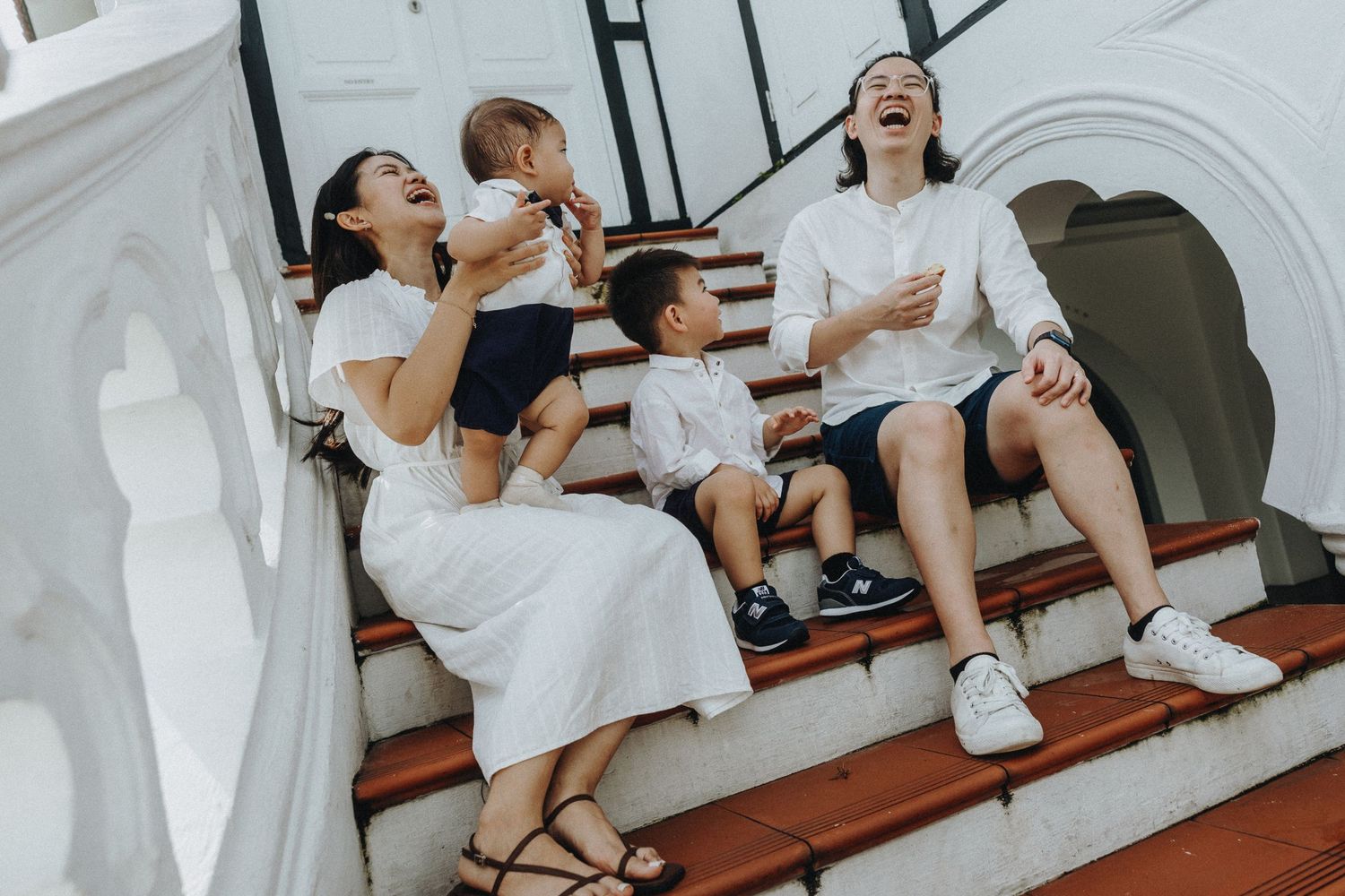 Happy family shares joyful moment together while sitting on wooden steps in bright hallway.