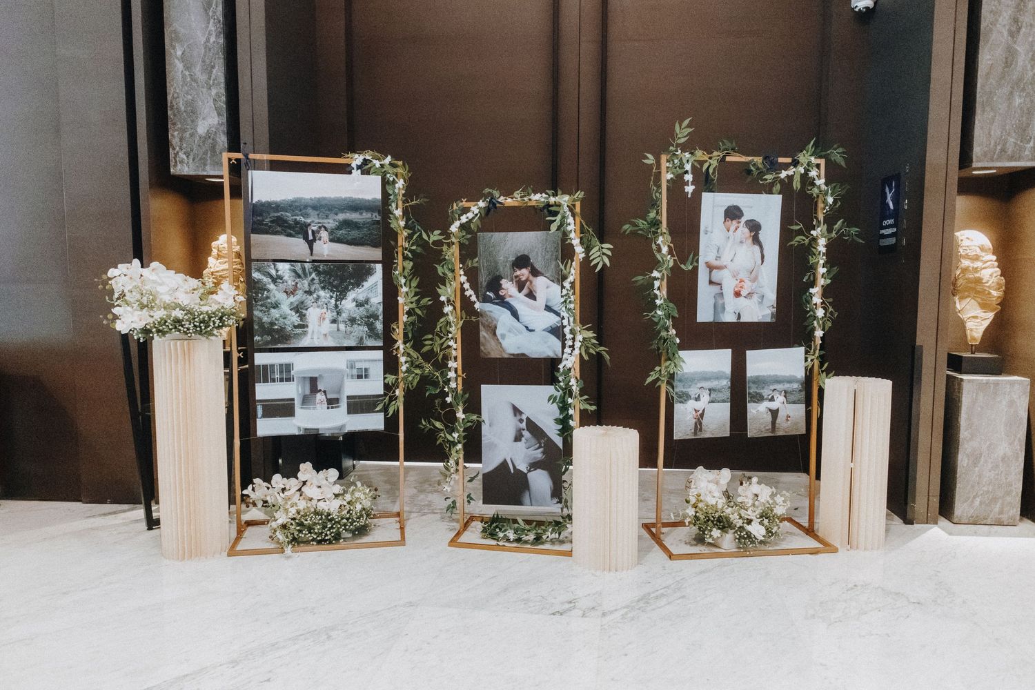 Decorative gold frames with photographs and floral accents sit elegantly on white floor against dark wood paneling.