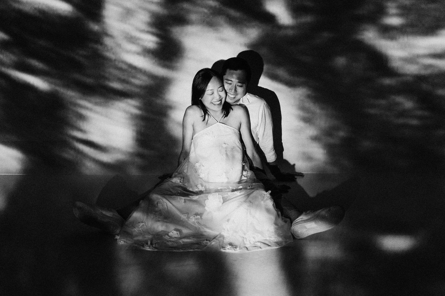 A dramatic black and white couples portrait with moody shadow patterns.