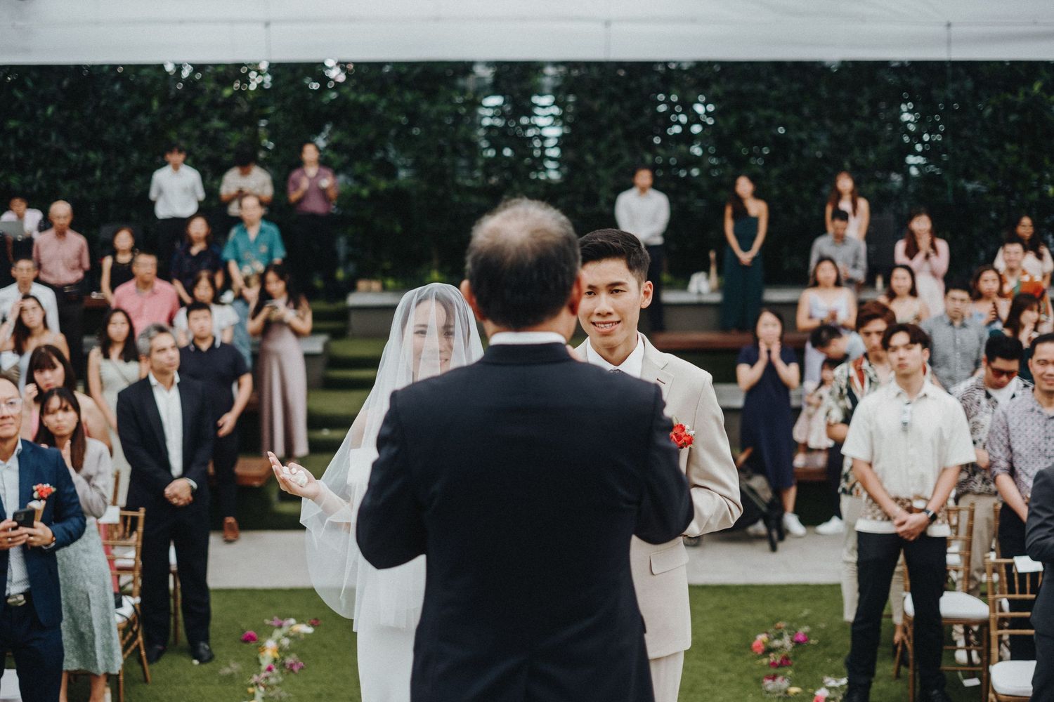 An outdoor wedding ceremony with guests seated on a lawn watching the proceedings.