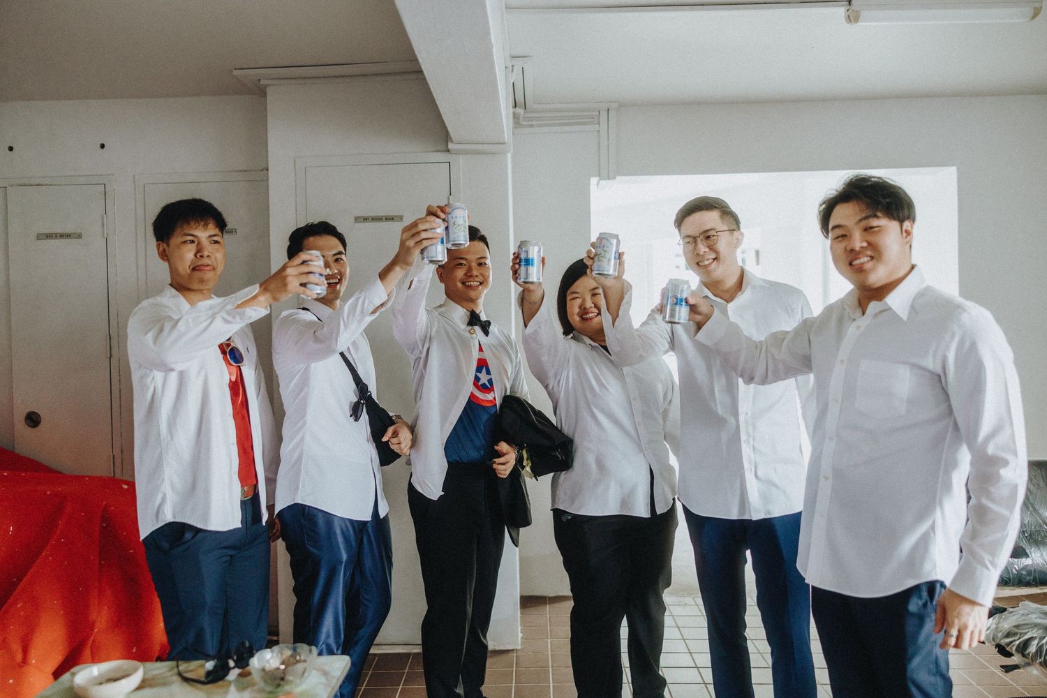 A group wearing white dress shirts playfully poses together in a bright indoor space.