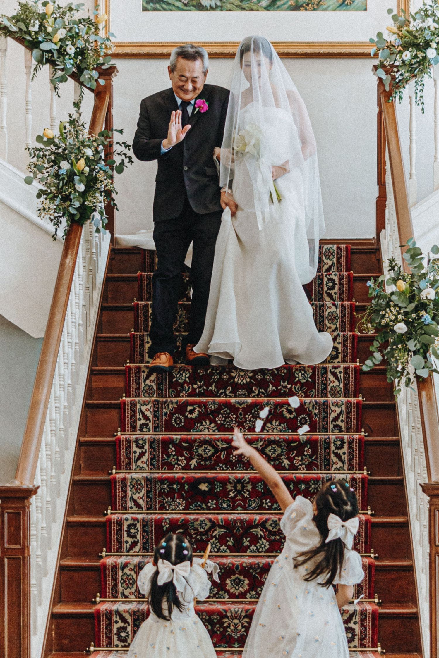 A sequence showing a bride and groom descending an elegant staircase decorated with floral arrangements.