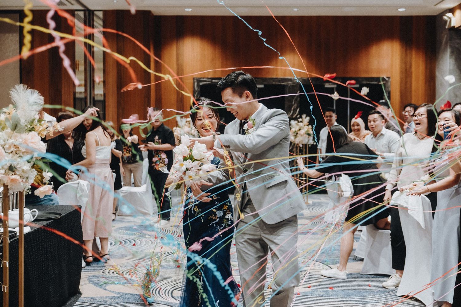 Wedding party celebration with streamers and confetti in an elegant banquet hall.
