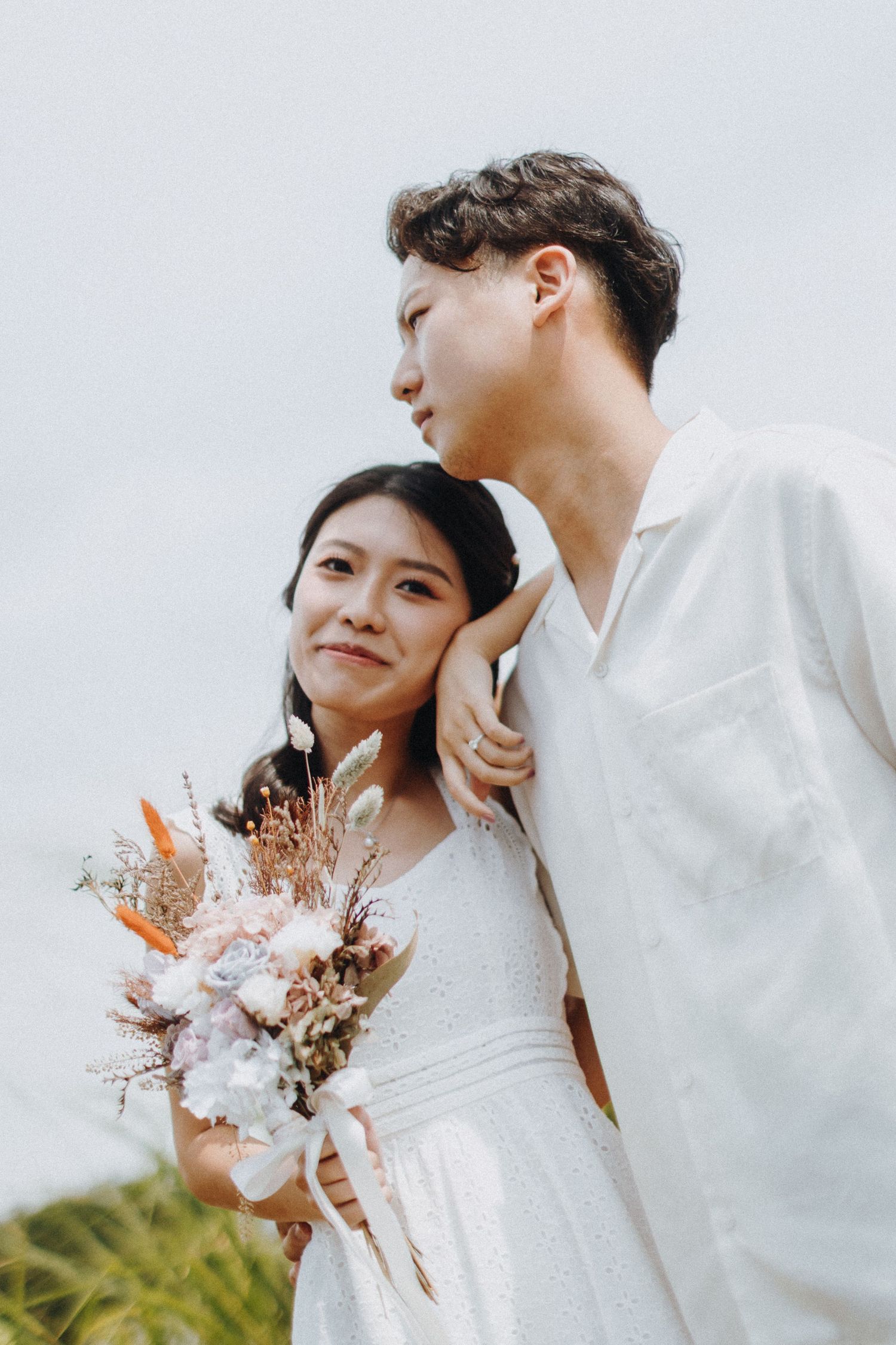 Romantic pre-wedding photoshoot with a delicate dried flower bouquet against a light background.