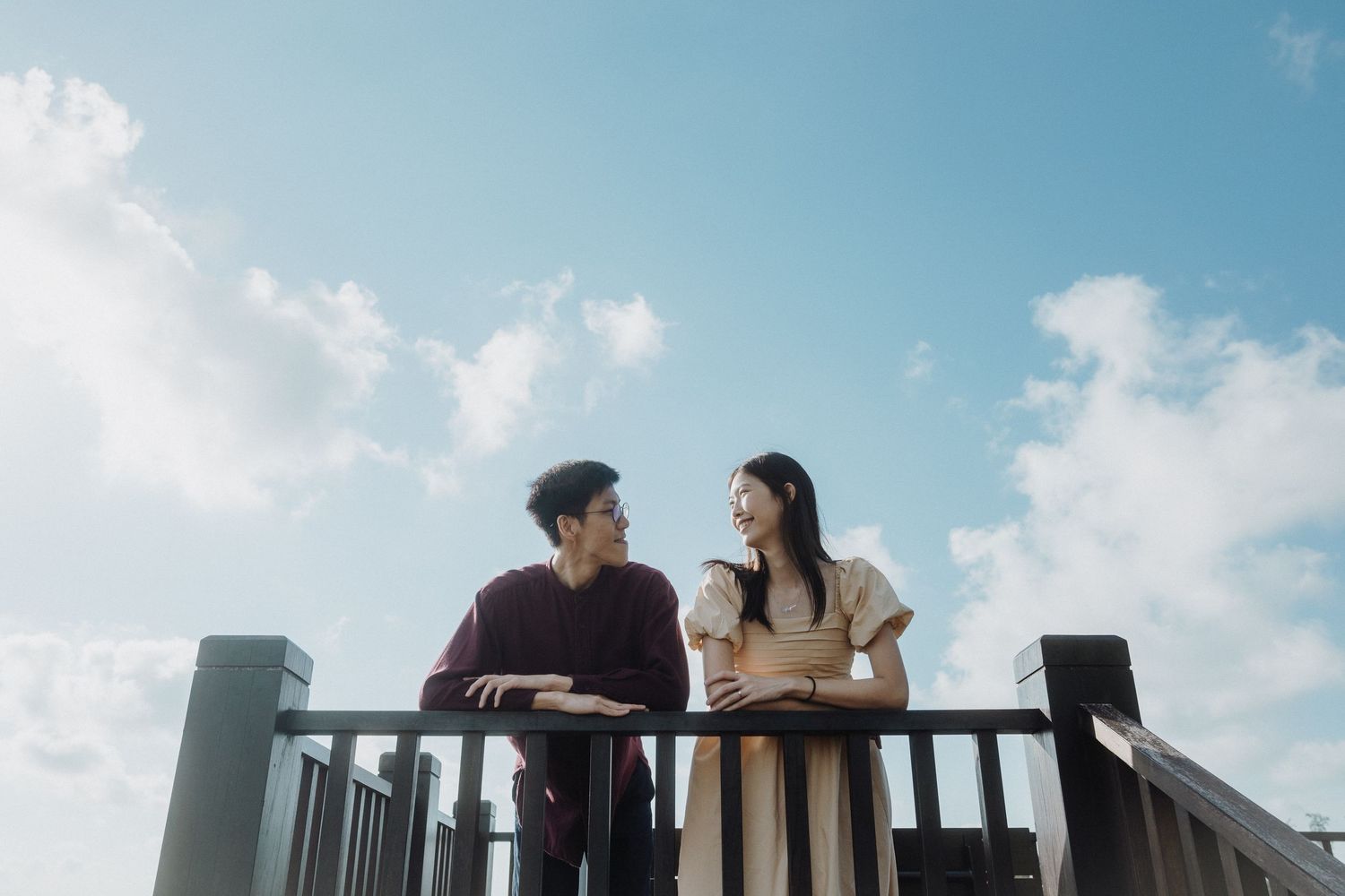 Couple sharing an intimate moment on a rooftop against a bright blue sky.