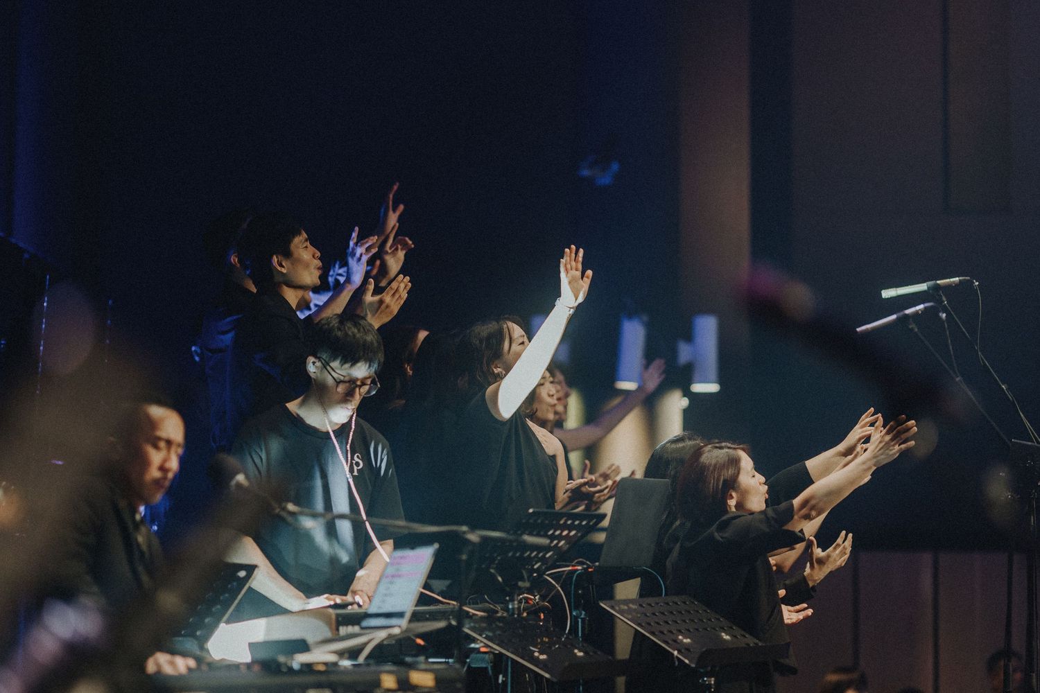 Musicians performing together with raised hands during an energetic concert performance.
