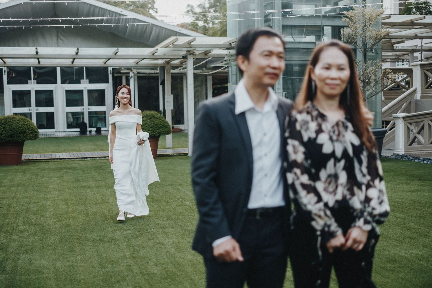 Joyful couple strolling hand in hand through a grassy outdoor setting on a sunny day.