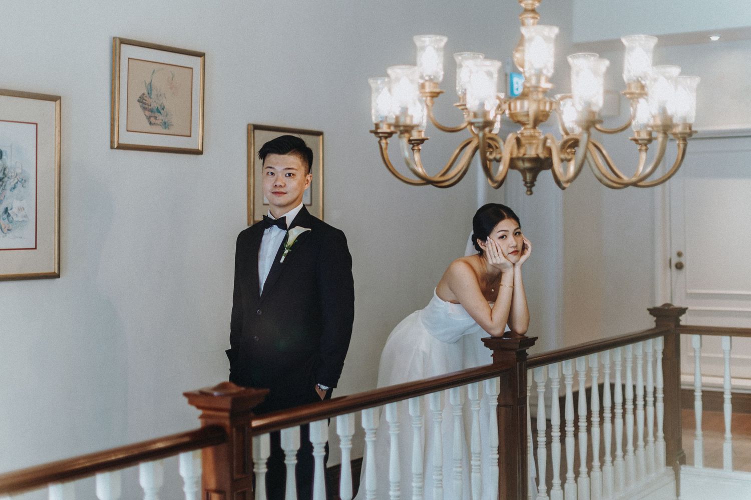 Wedding ceremony setting with a grand staircase, elegant chandelier, and white decor in a classic interior.