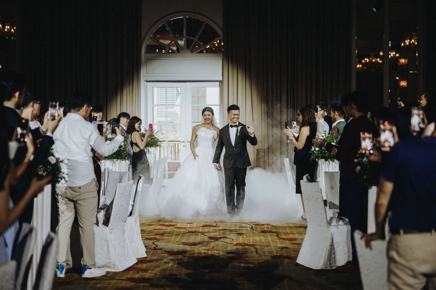 Wedding reception scene with guests and decorative lighting in an elegant venue.