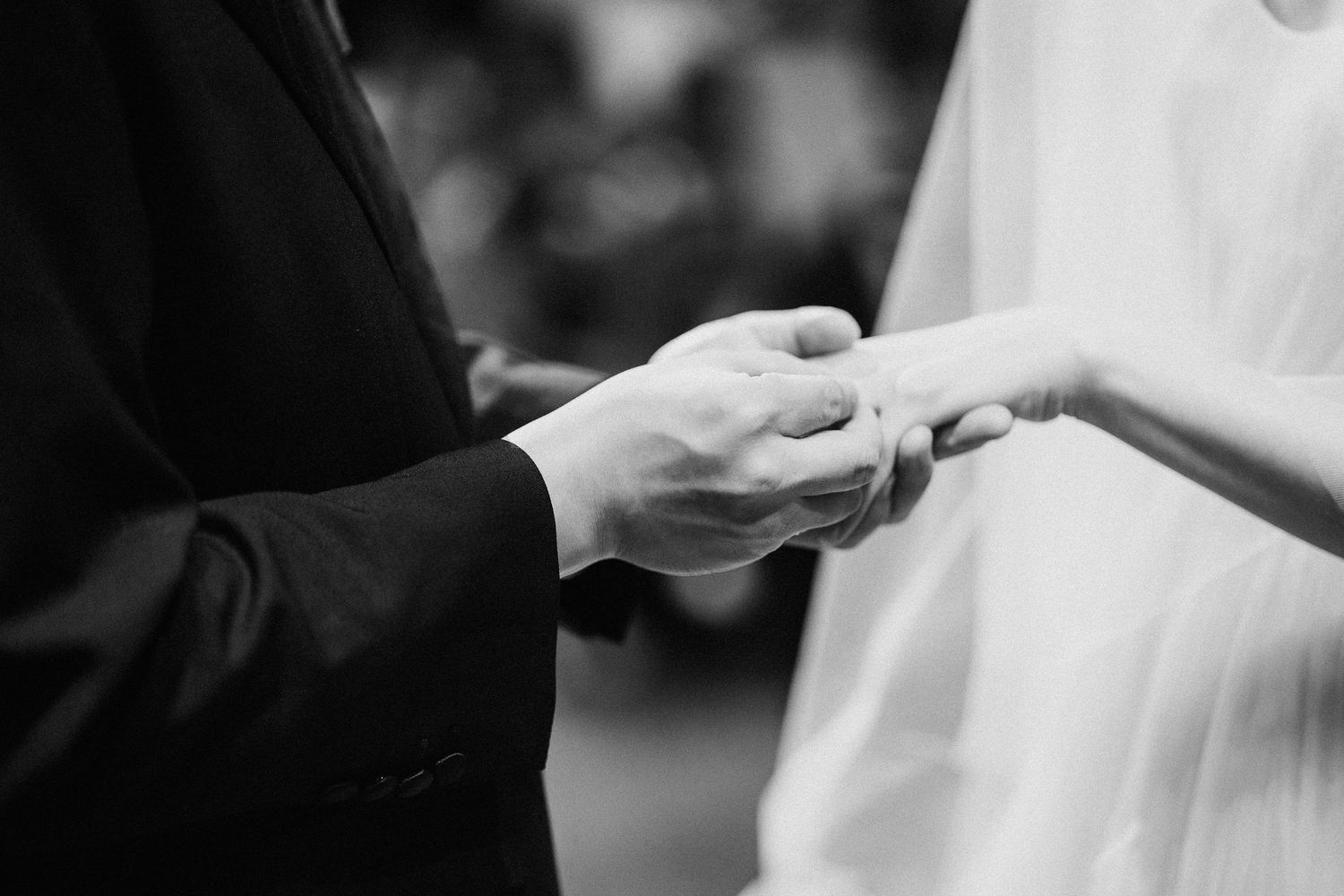 Black and white wedding ceremony photo capturing an emotional moment during ring exchange.