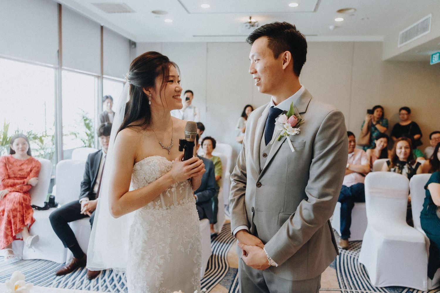 A couple exchanges vows during their wedding ceremony in a bright indoor venue.
