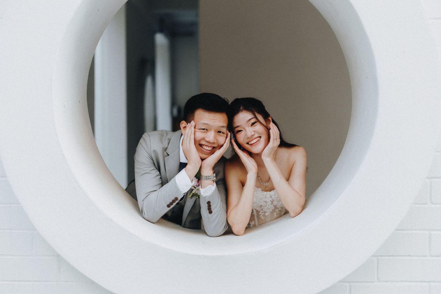 Minimalist photo series showing couple posing playfully through white circular frames against light wall.