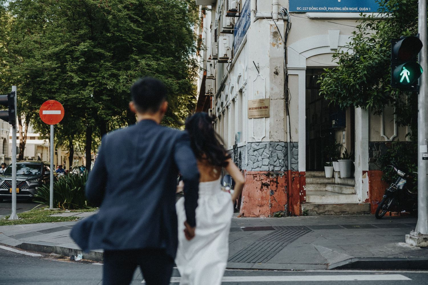 Two people stand close together on a city street corner near an old building in soft daylight.