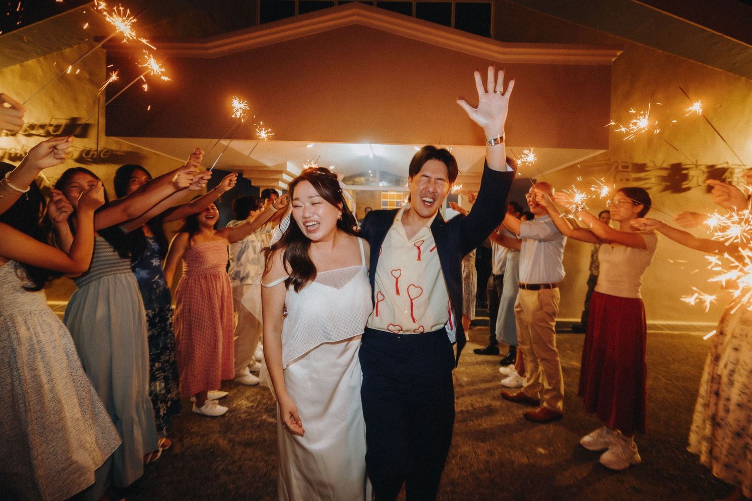 Wedding party celebrating with sparklers creating magical light trails in evening setting.