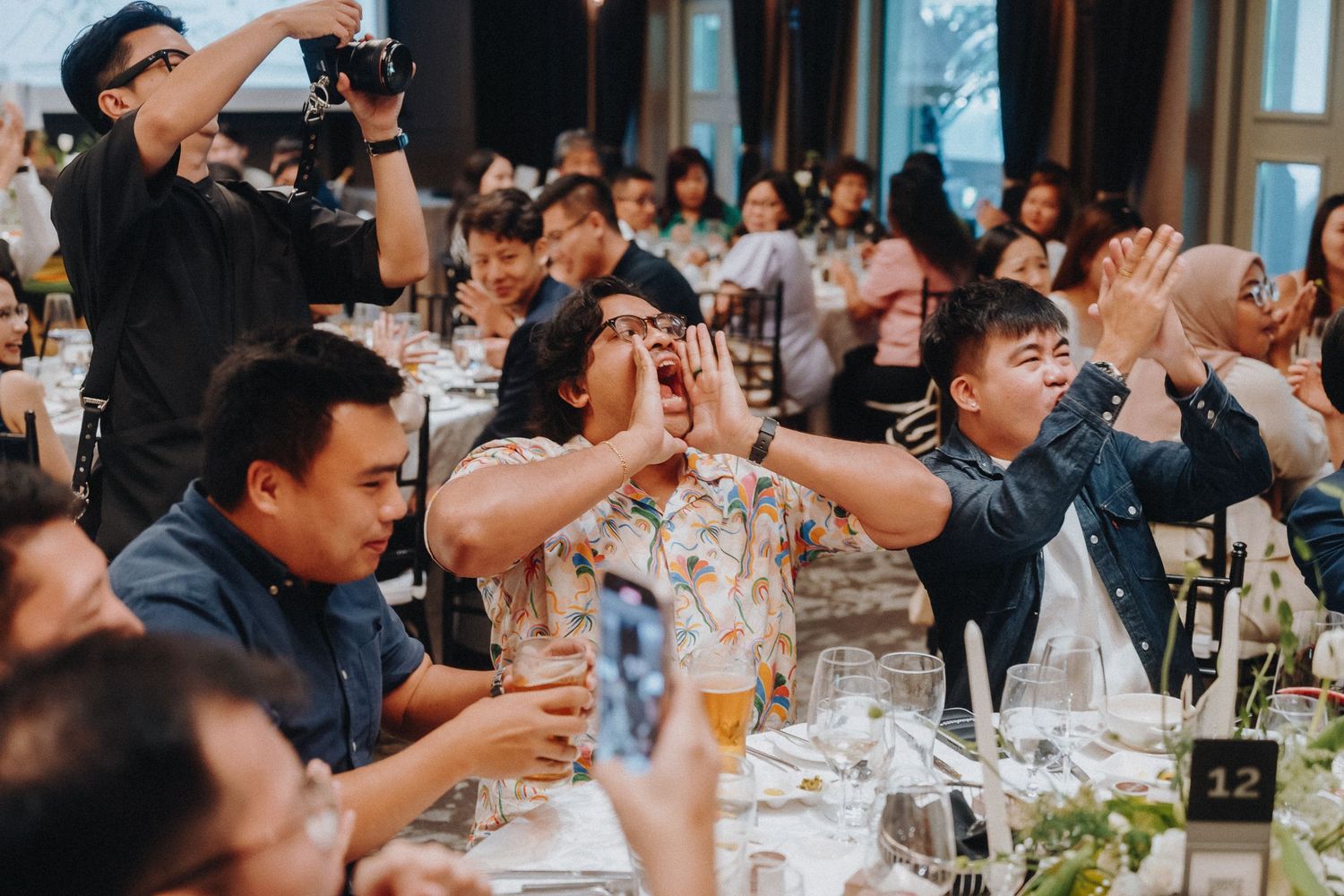 Multiple photographers with cameras capture moments at a wedding reception celebration.