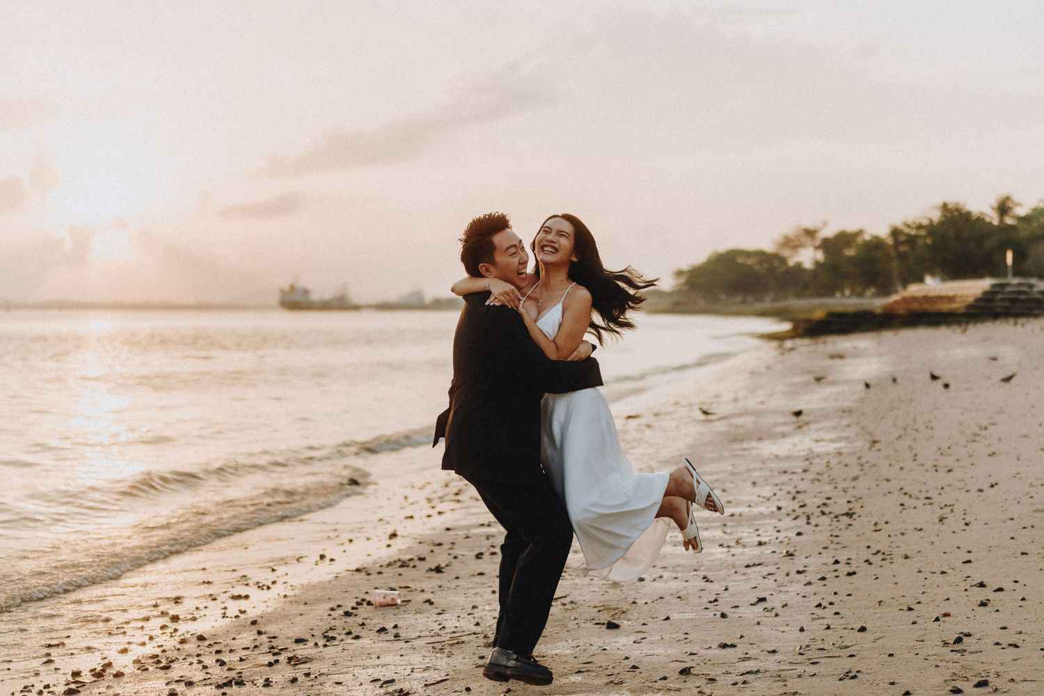 Romantic beach photoshoot with couple enjoying tender moments at sunset.