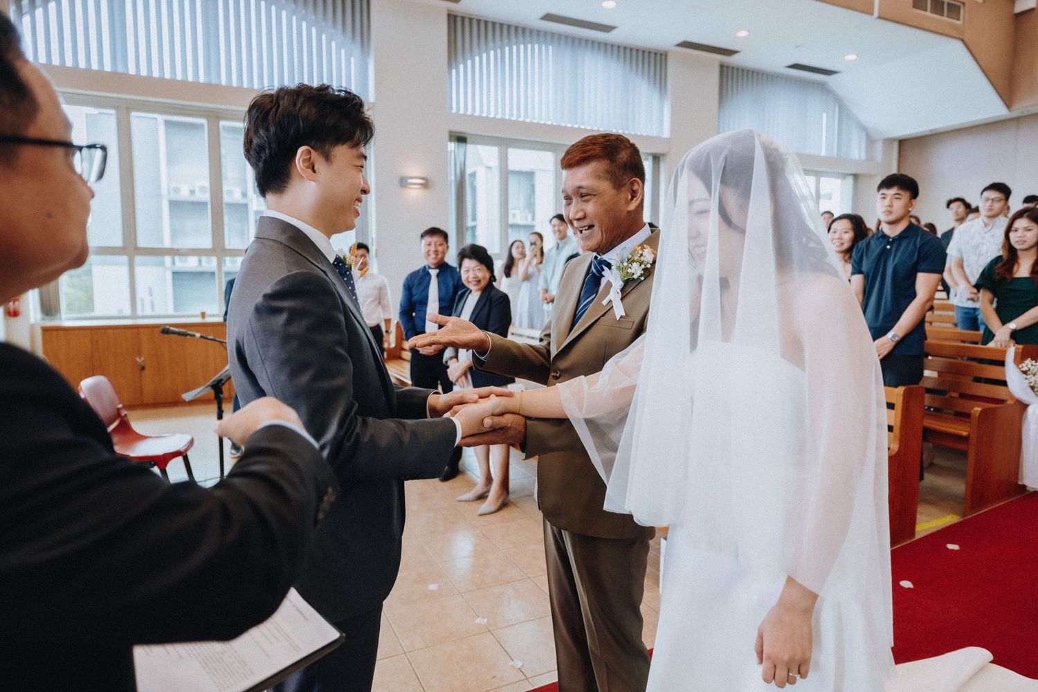 Father of bride handing off daughter to groom during church wedding ceremony.