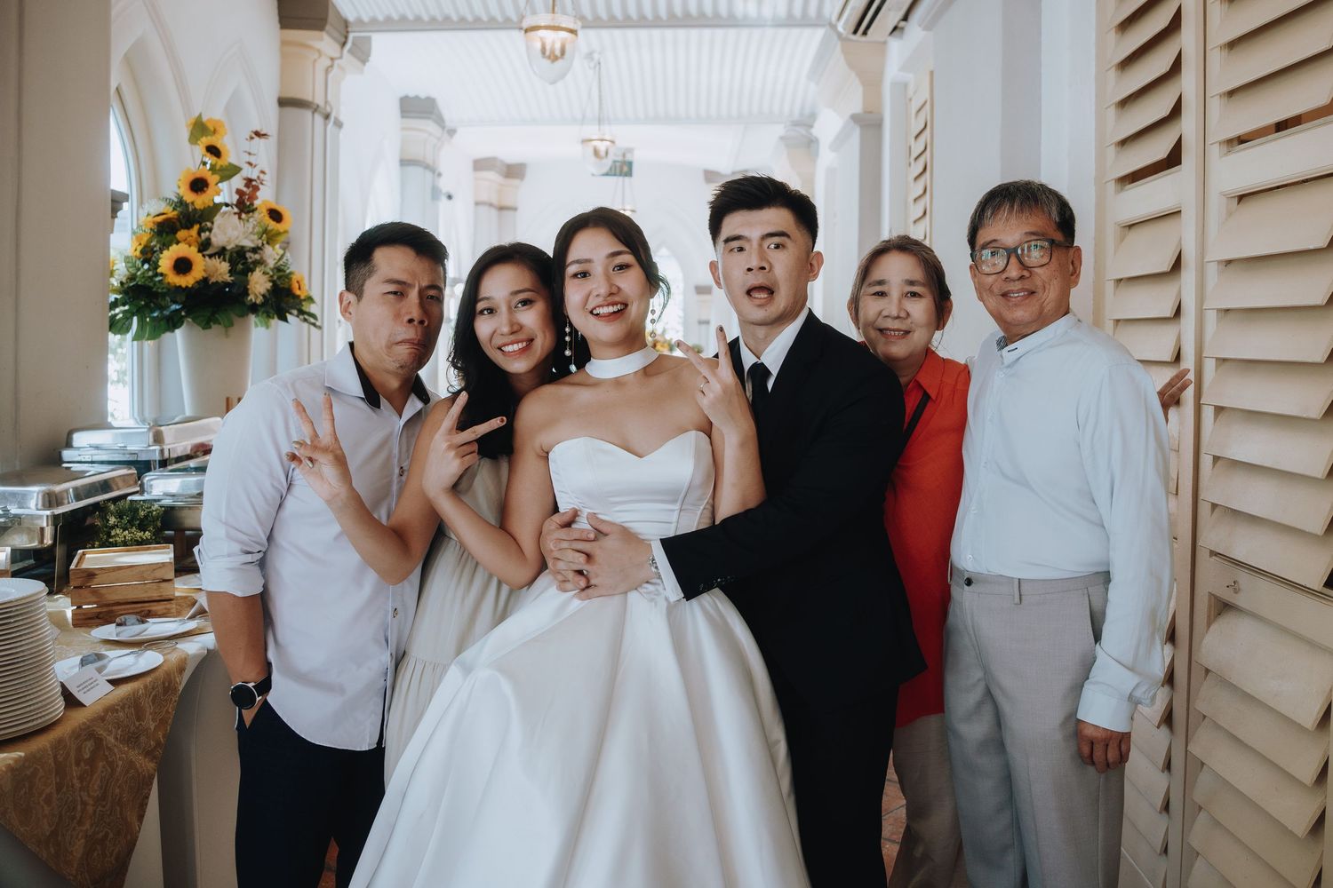 Bride and groom pose joyfully with family members at a wedding reception.