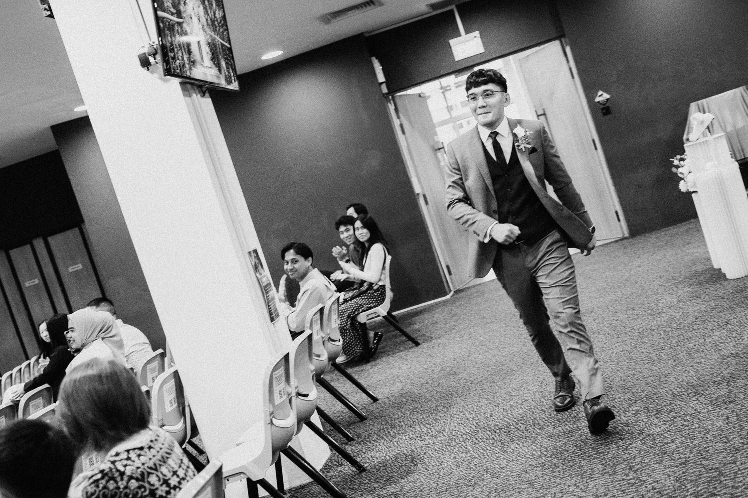 Black and white candid shots capturing movement in a wedding venue hallway.