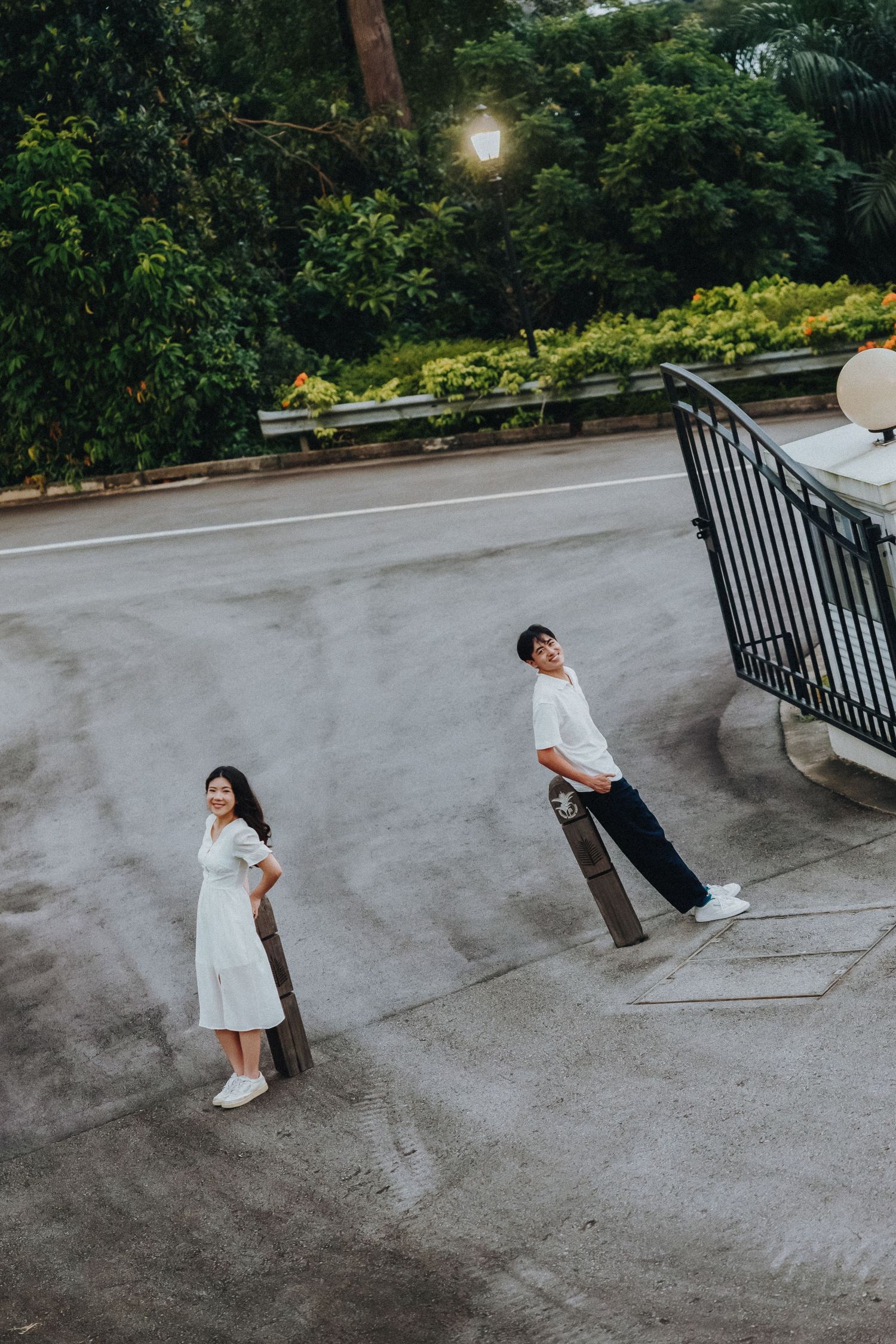 A creative aerial shot of a couple in white outfits standing apart on concrete ground.